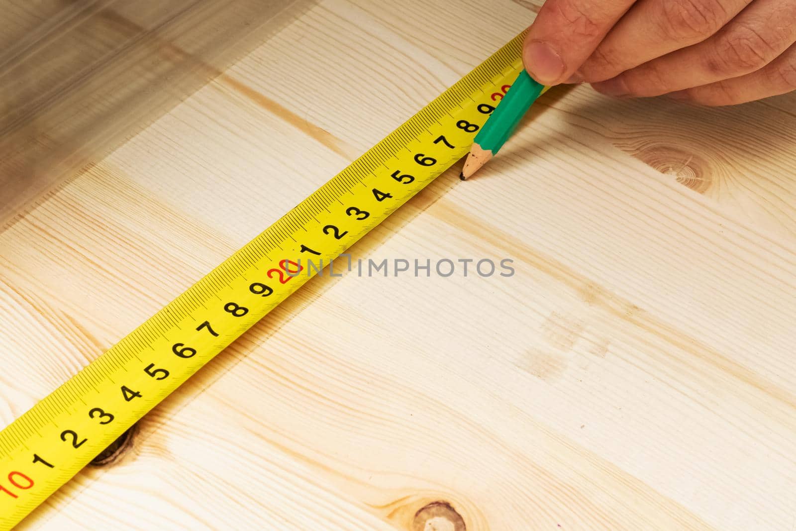 Marking with a pencil and a ruler on a wooden board close up