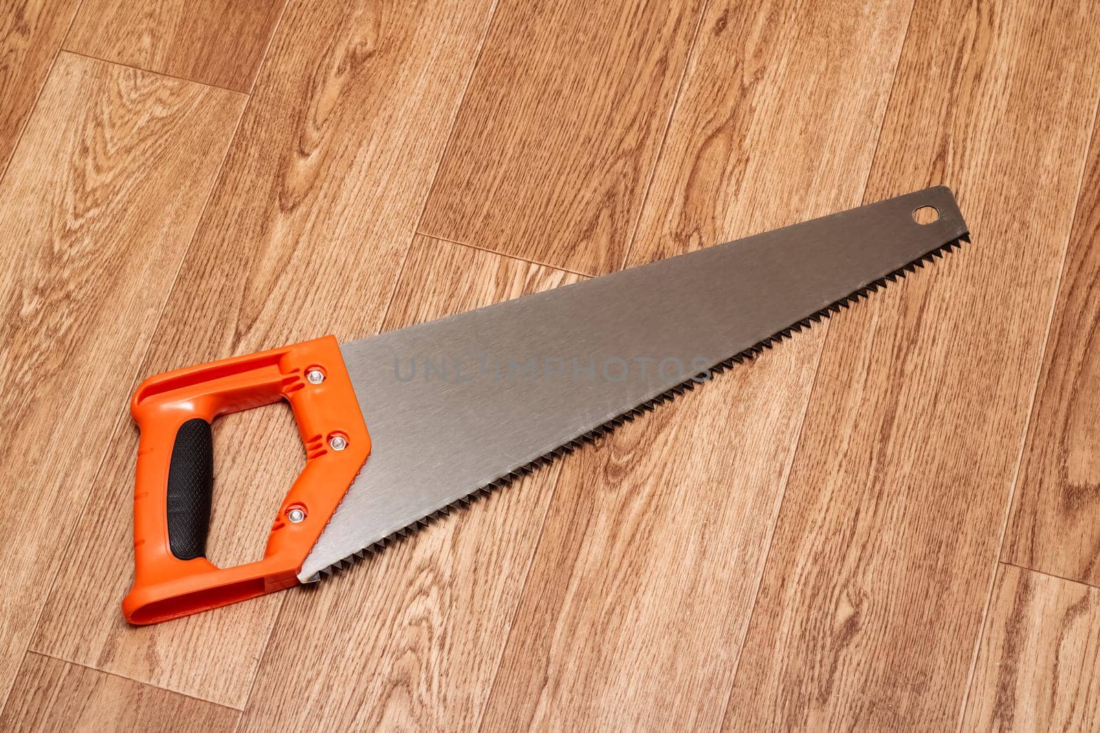 Saw with a plastic handle on a wooden table close up