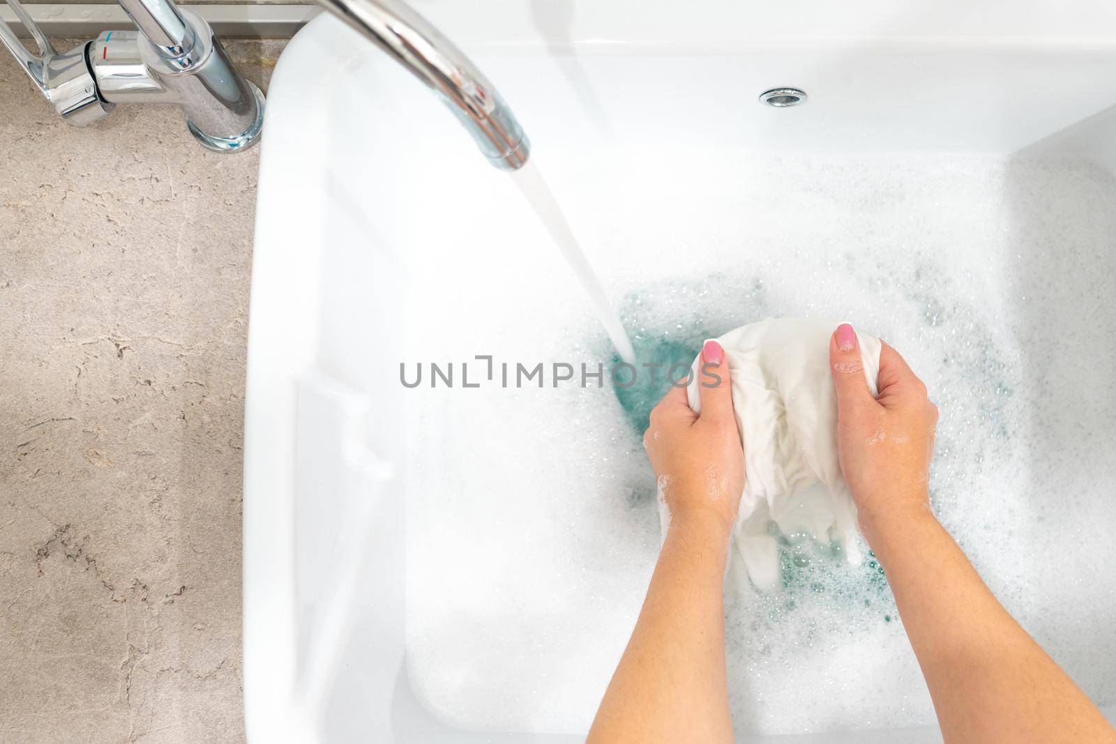 Female hands washing color clothes in basin