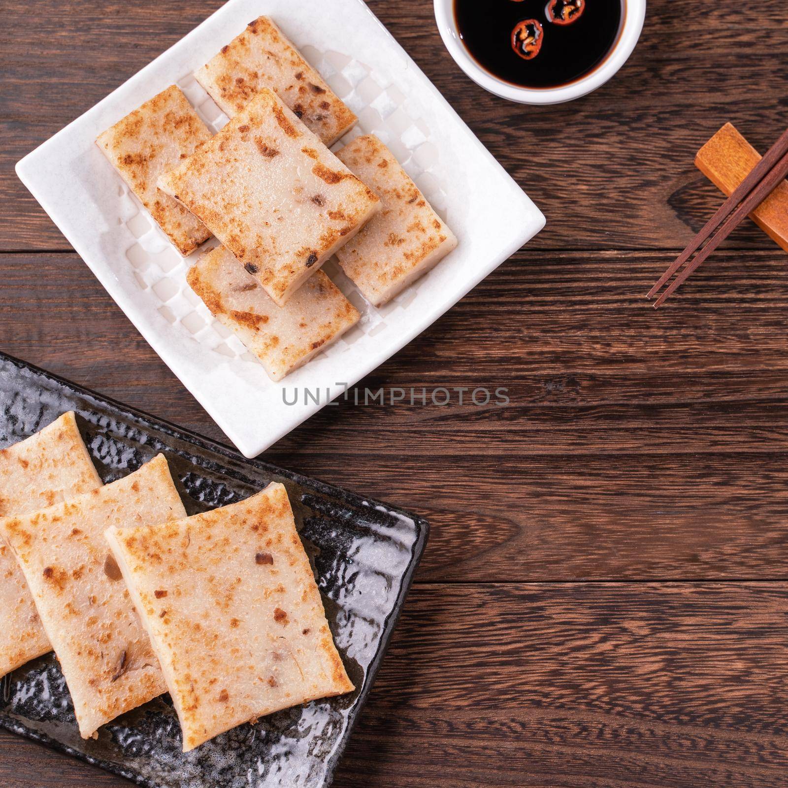 Delicious turnip cake, Chinese traditional local radish cake in restaurant with soy sauce and chopsticks, close up, copy space, top view, flat lay.