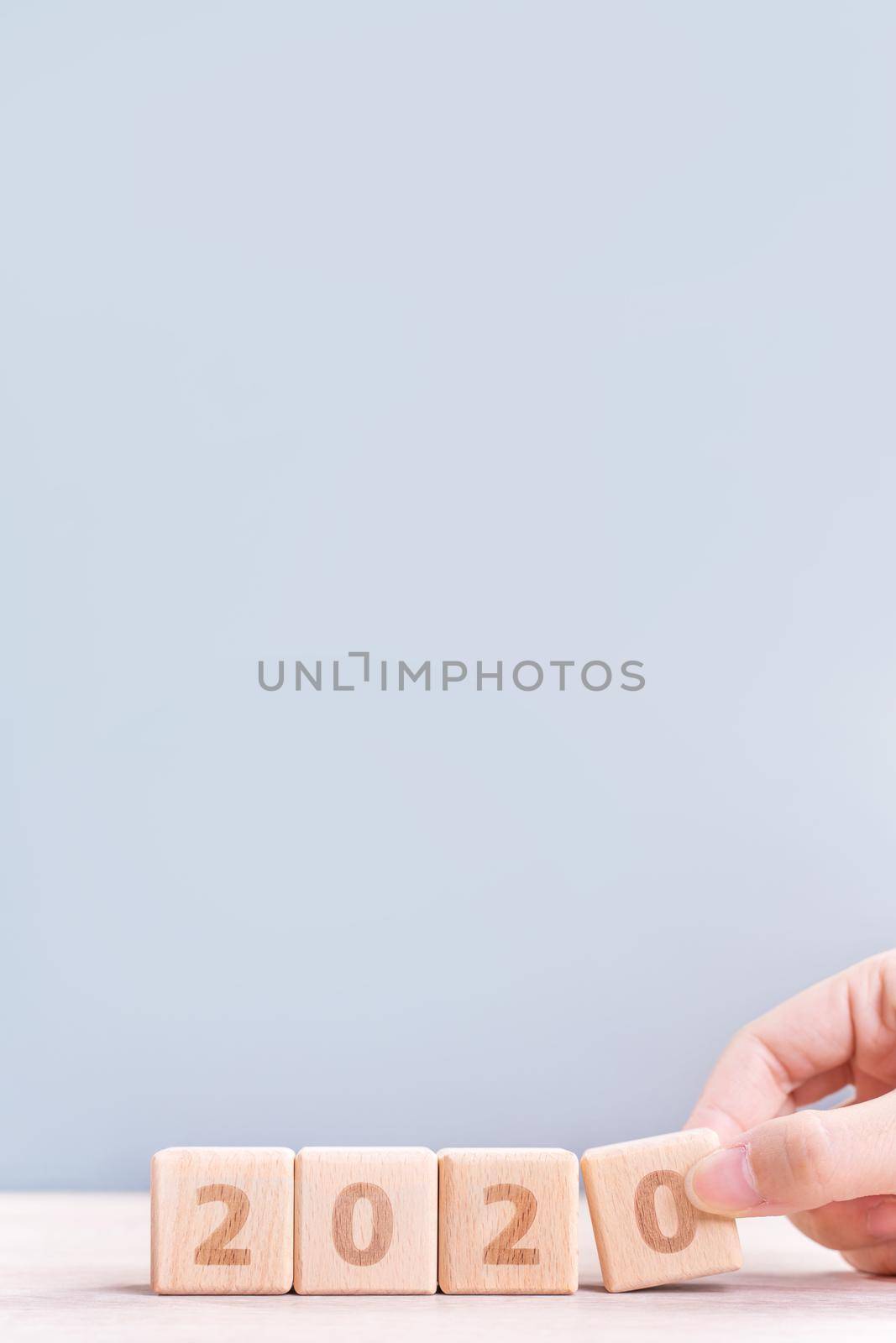 Abstract 2020 & 2019 New year countdown design concept - woman holding wood blocks cubes on wooden table and blue background, close up, copy space.