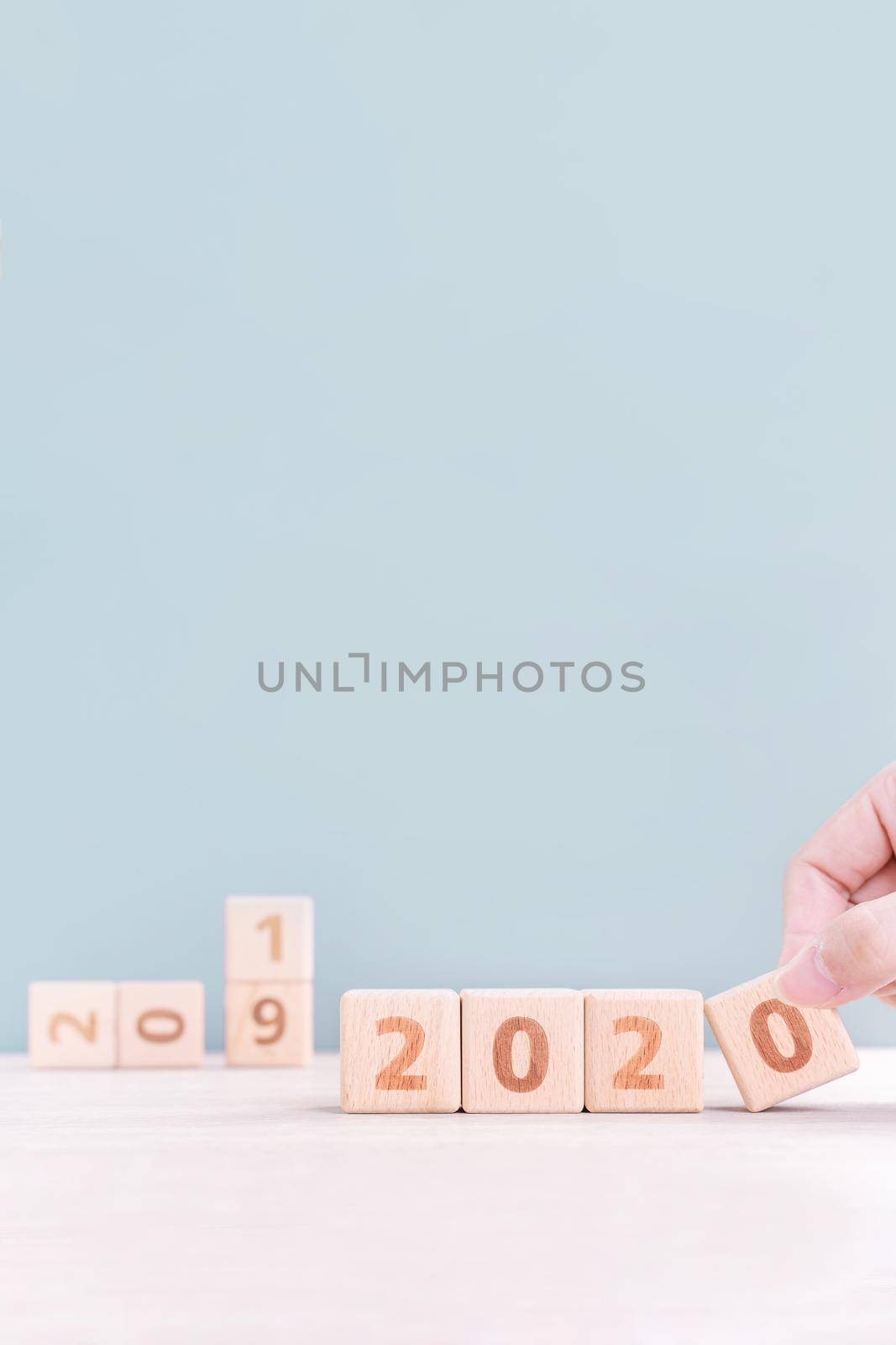 Abstract 2020 & 2019 New year countdown design concept - woman holding wood blocks cubes on wooden table and green background, close up, copy space.