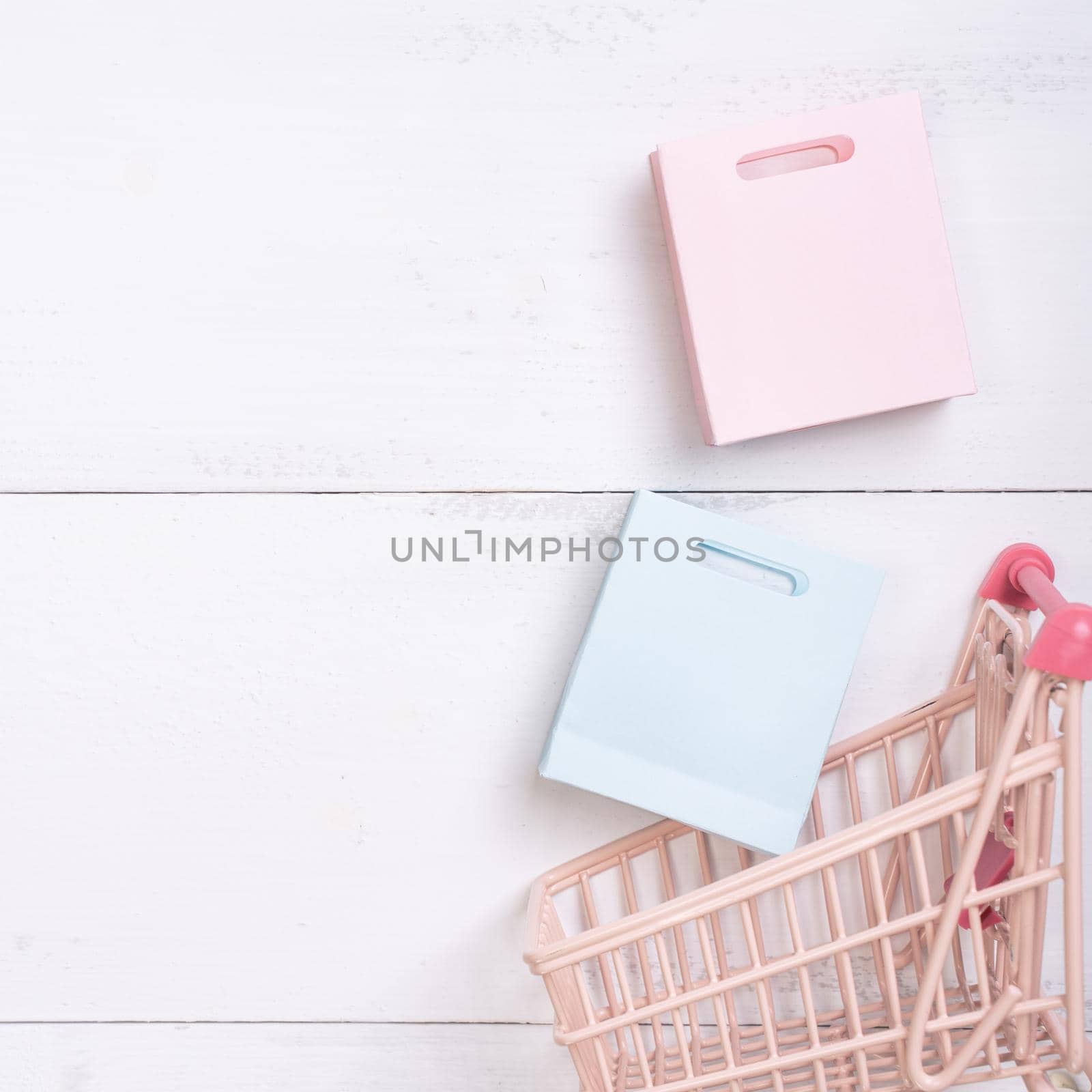 Abstract design element,annual sale,shopping season concept,mini cart with colorful paper bag on white wooden table background,top view,flat lay