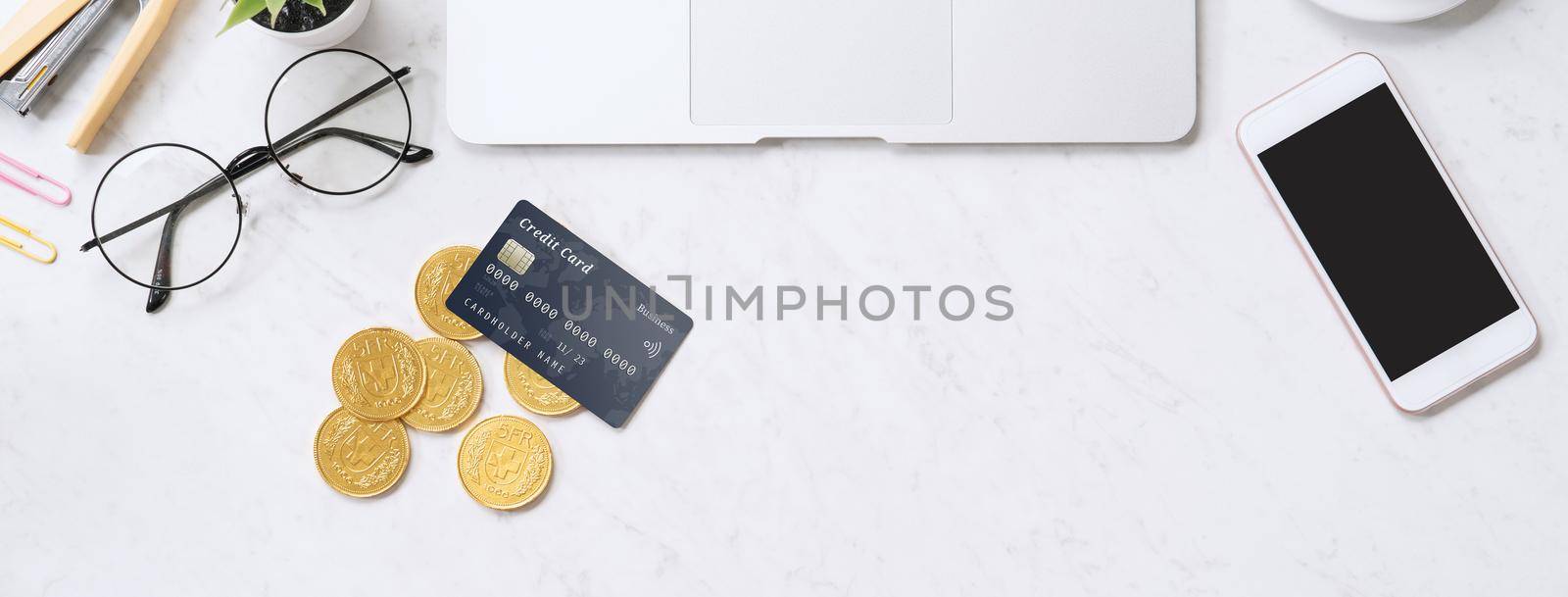 Concept of online payment with credit card with smart phone, laptop computer on office desk on clean bright marble table background, top view, flat lay