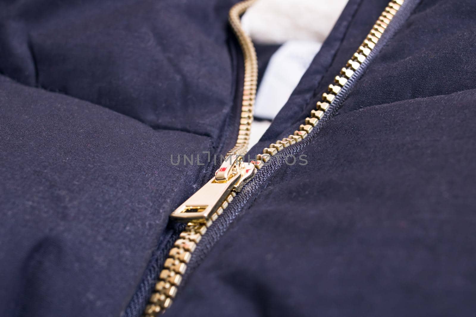 Metallic yellow zipper on a black jacket close up