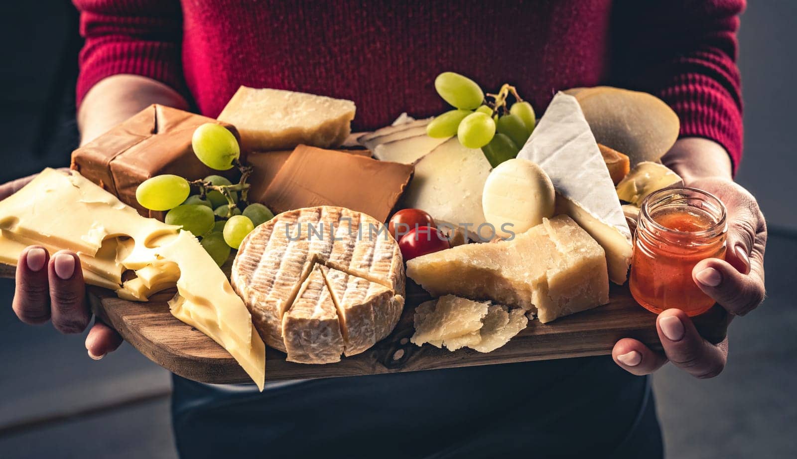 Girl holding different kinds of cheese and honey on wooden table in hands closeup. Woman with organic parmesan and brie set french delicatessen