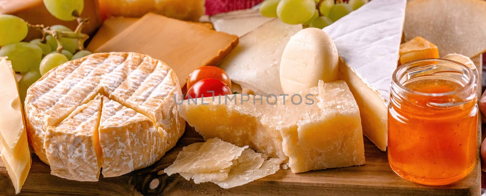 Parmesan and different kinds of cheese served with grapeand honey closeup. Organic brie and camambert set delicatessen collection