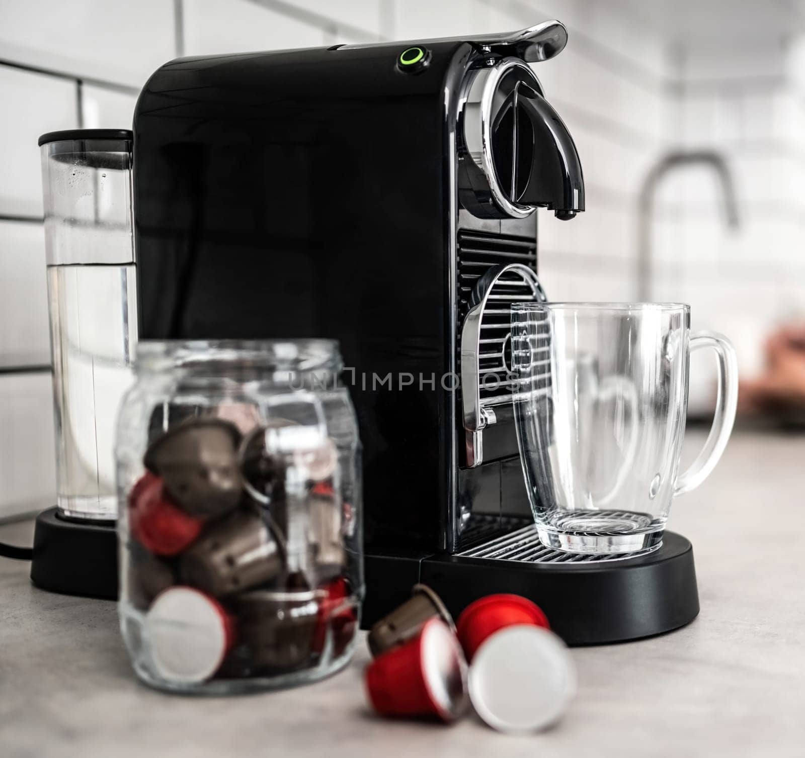 Coffee machine with capsules and transparent cup at domestic kitchen at home. Espresso caffeine beverage maker and modern mug