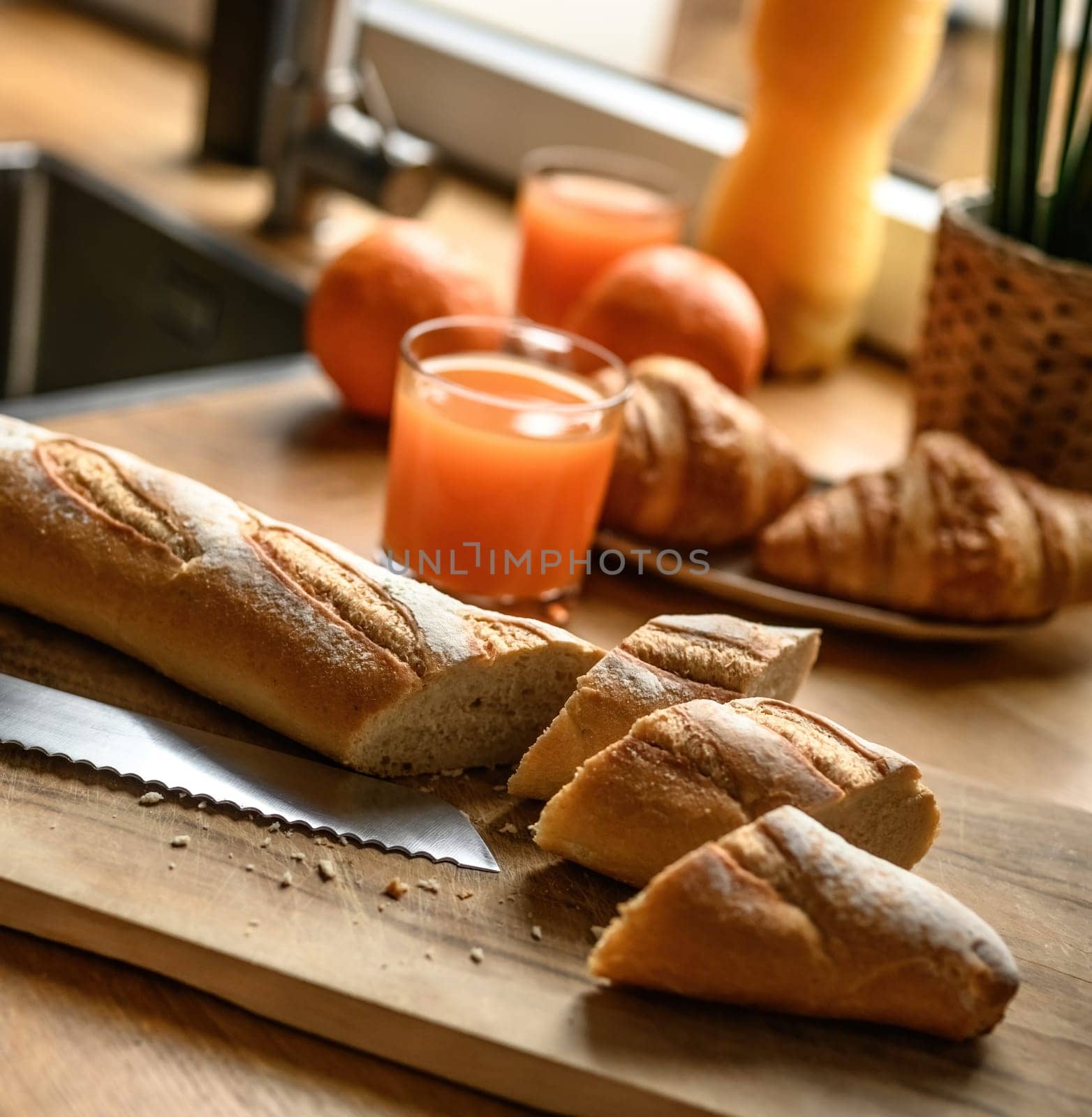 Fresh baguette on a cutting board at the kitchen. Cooking fresh french breakfast.