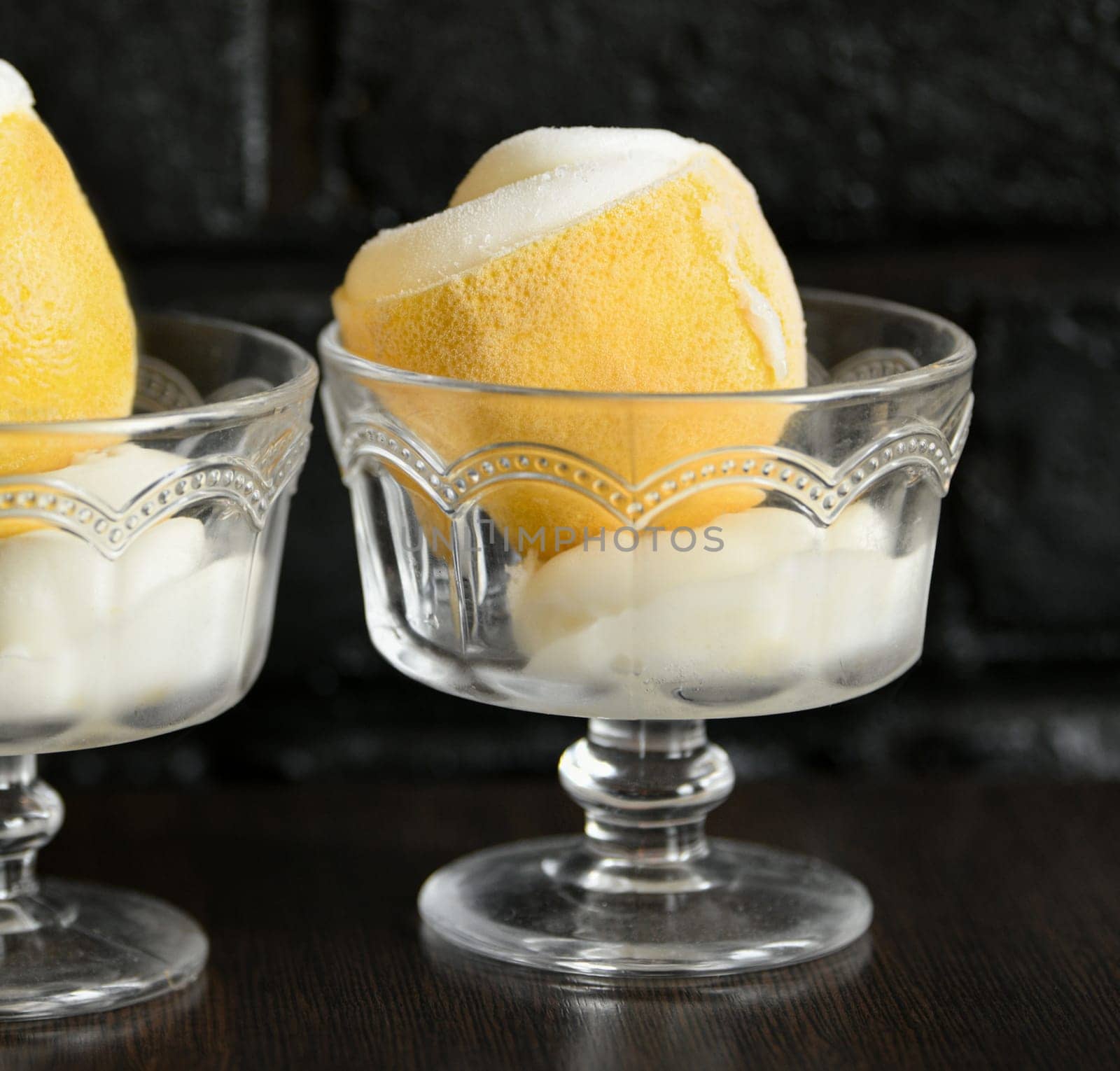 Ice cream sorbet in lemon and glass on black background