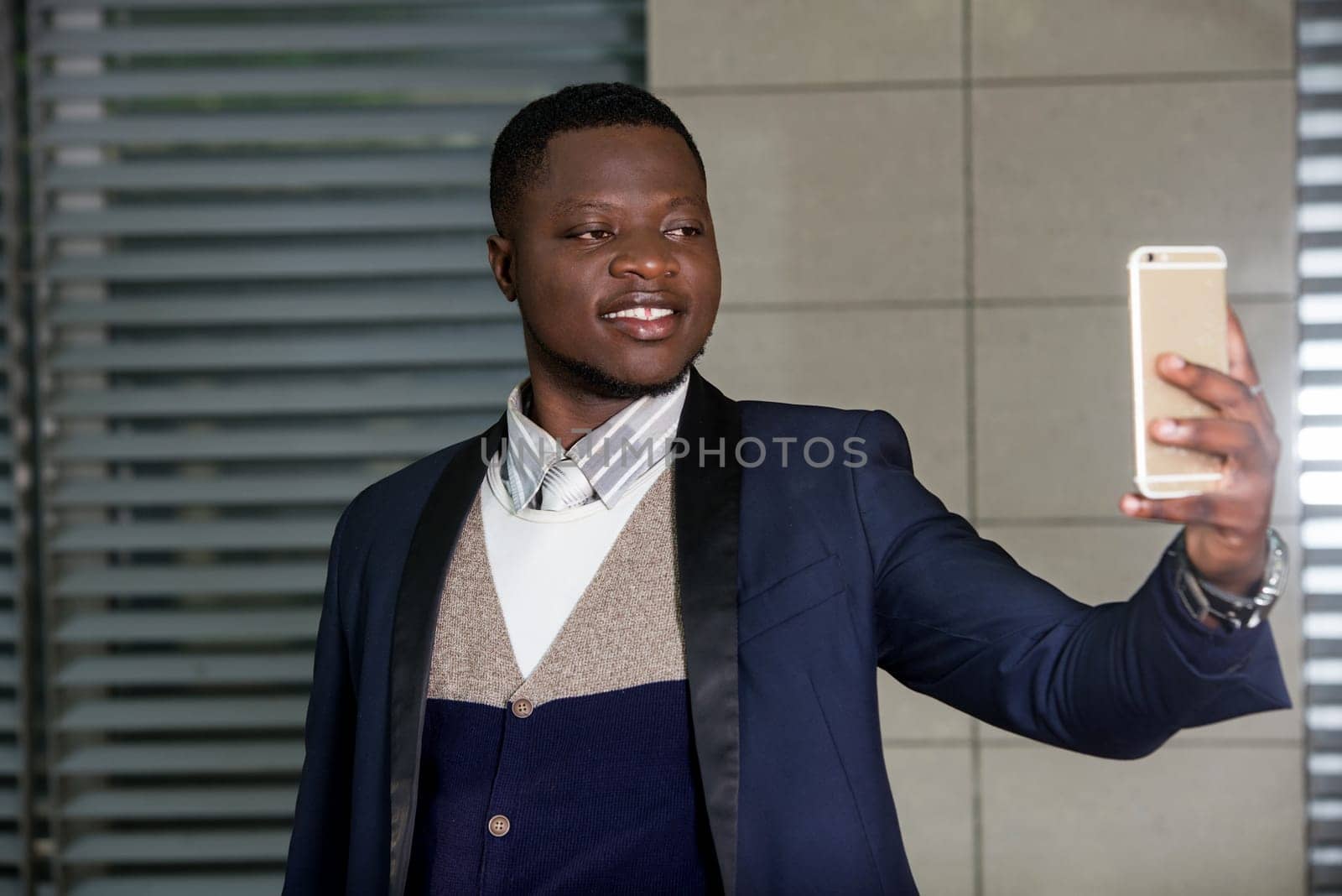 young man standing in a suit looking at cell phone while smiling.