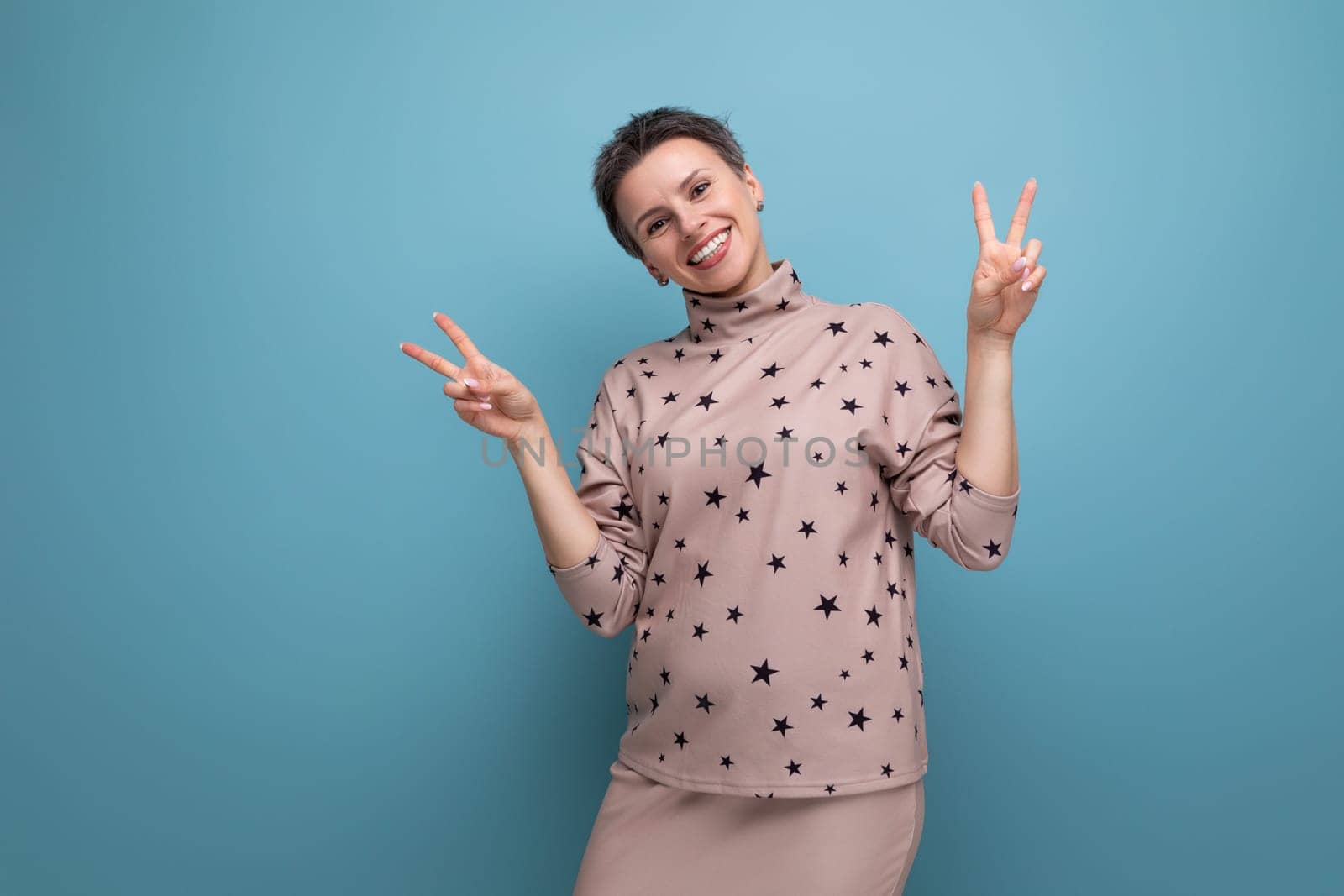 successful 30 year old european business woman with dyed gray hair in a skirt and blouse smiling on a blue background with copy space.