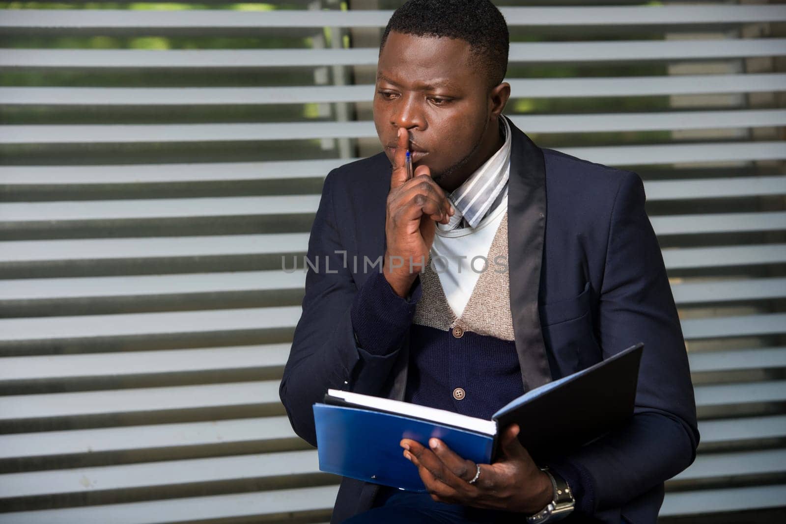 Portrait of handsome man in suit making notes on workplace outside. by vystek