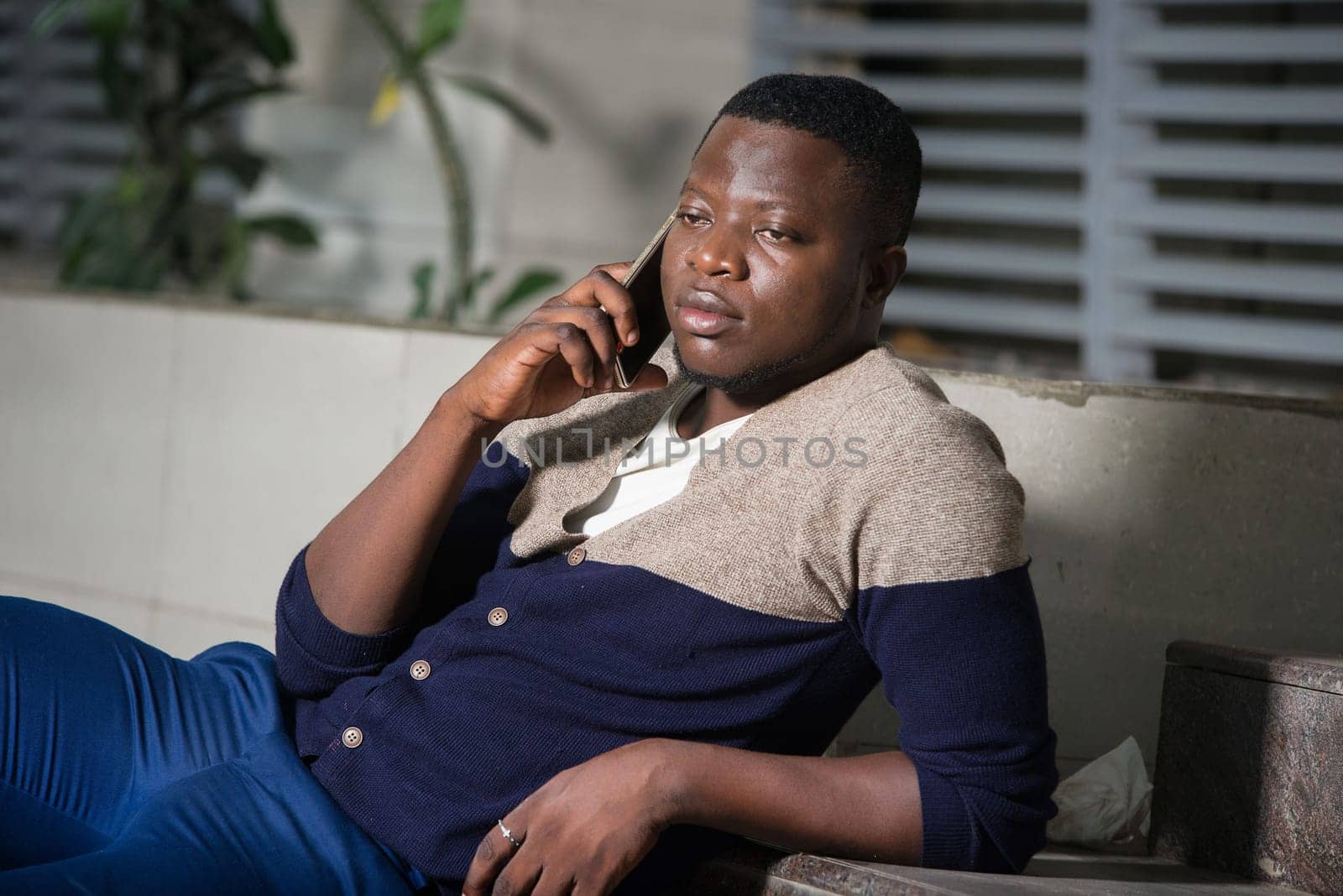 young formal formal dressed man talking on the phone while lying on a stairs outside