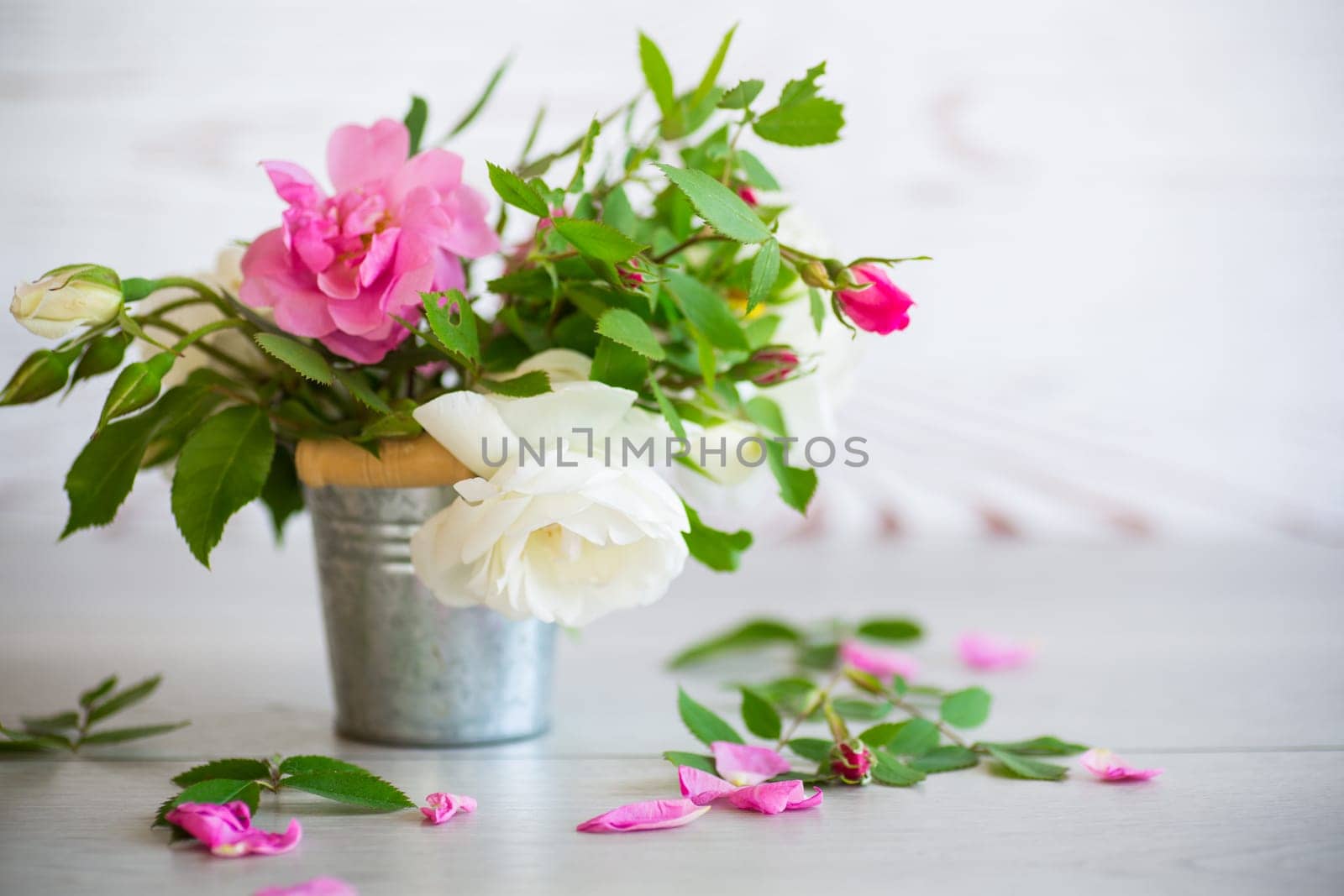 A small bouquet of beautiful summer pink and white roses on a light wooden background.