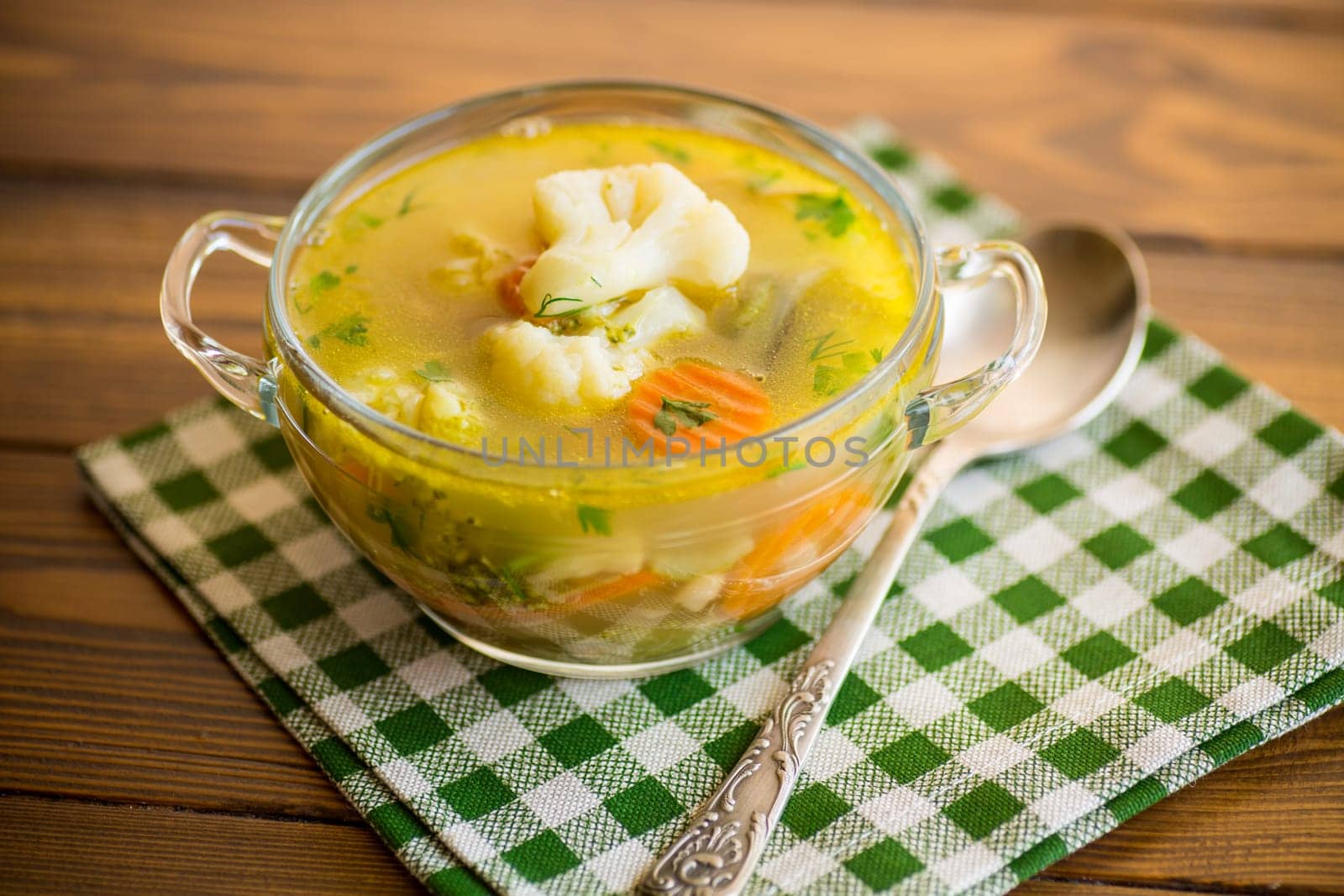 cooked chicken soup with cauliflower and vegetables in a bowl on a wooden table
