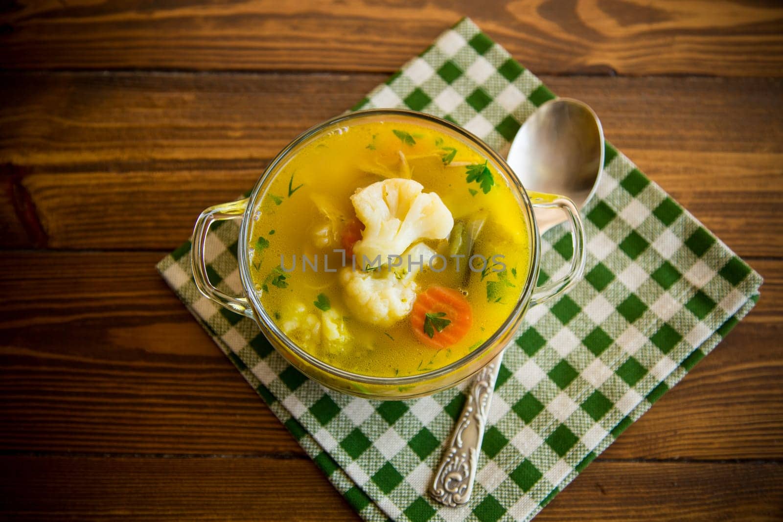 cooked chicken soup with cauliflower and vegetables in a bowl on a wooden table