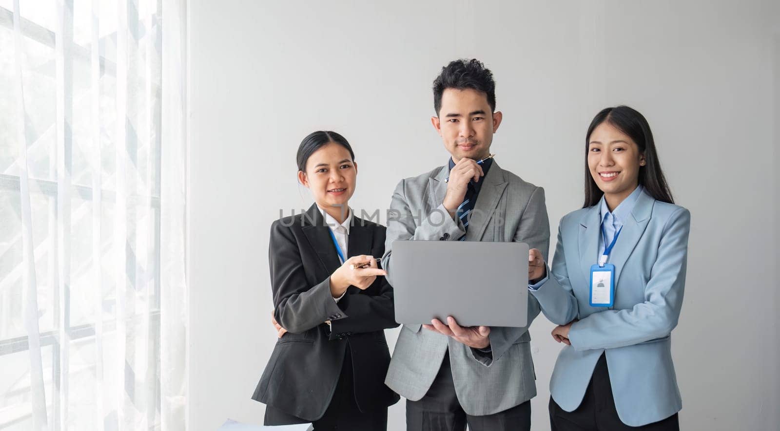 Solving problems as one team. Asian young team of male and female working together while sitting at their working place in office, enjoy, looking at the camera...