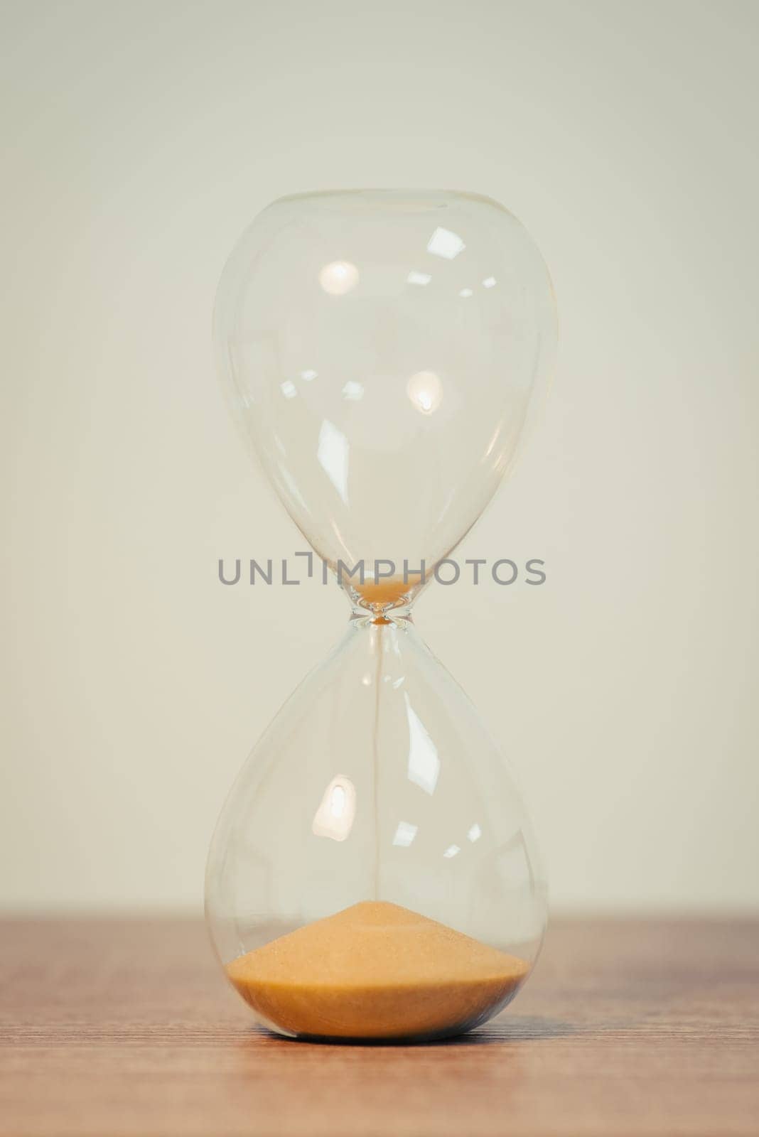 Sandglass on the white background, on wooden table, close up, vertical shot by VitaliiPetrushenko