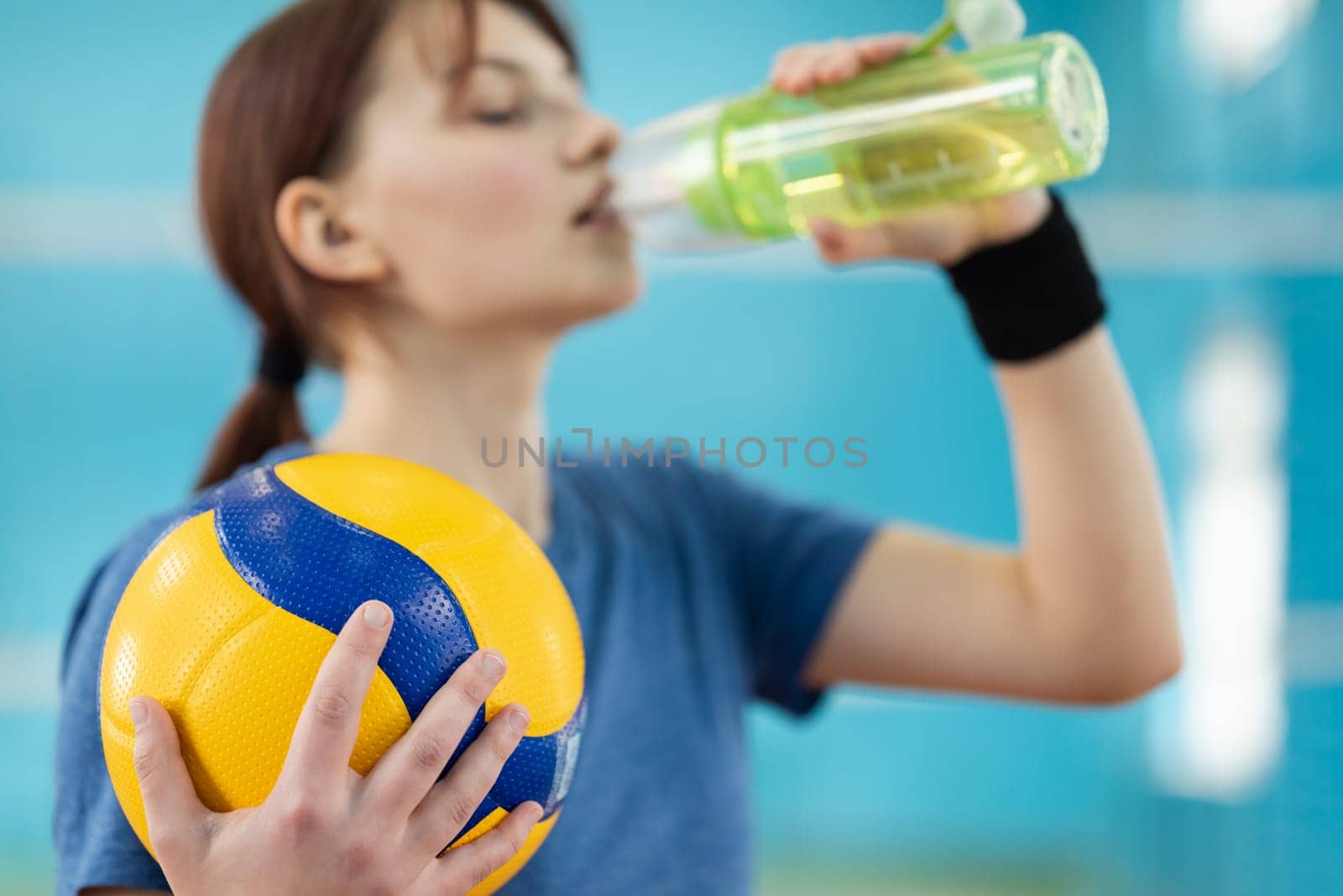 Girl drinking water during volleyball training, focus on the ball in hands