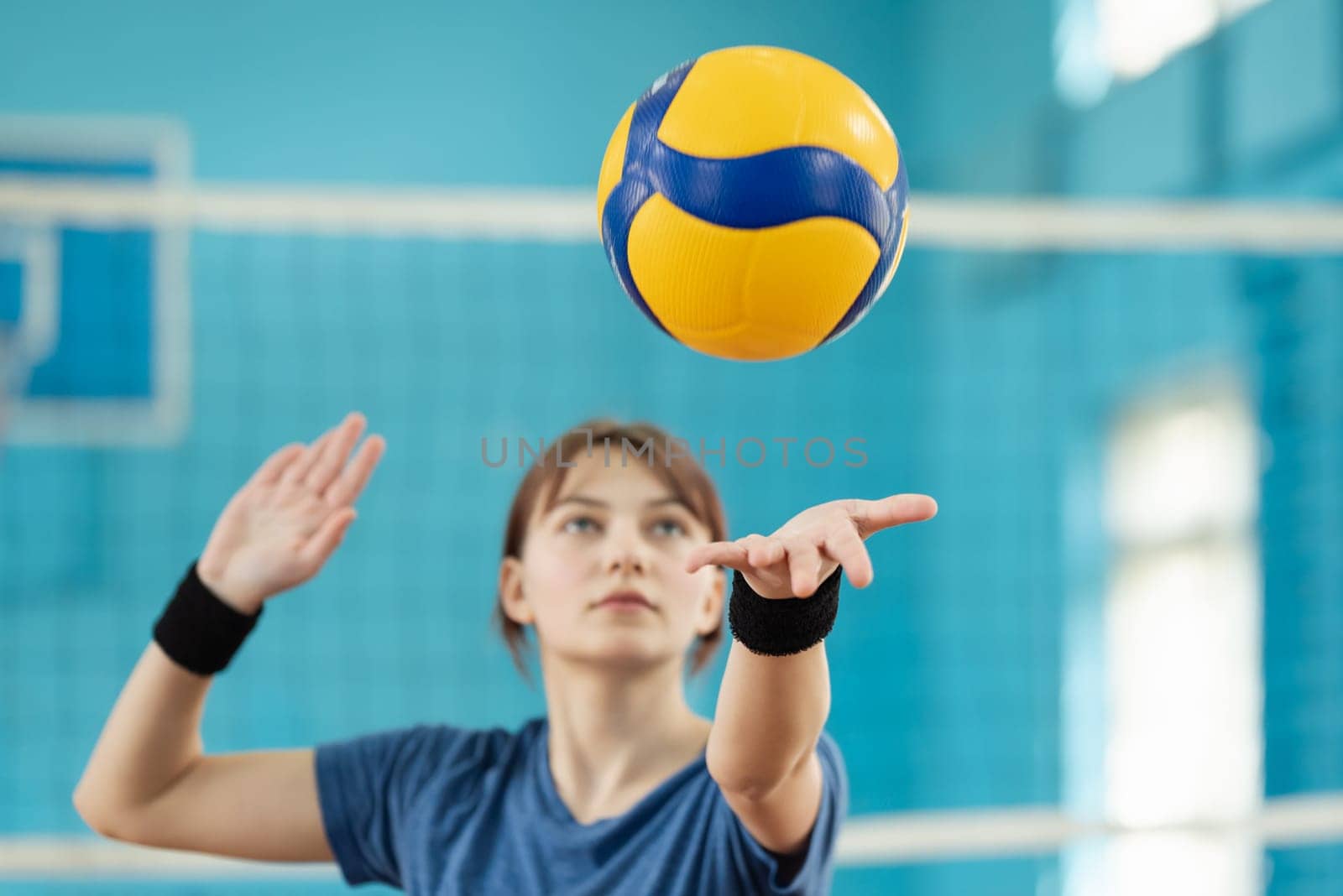 Learner practicing fundamental volleyball skill, serving the ball to opponents side