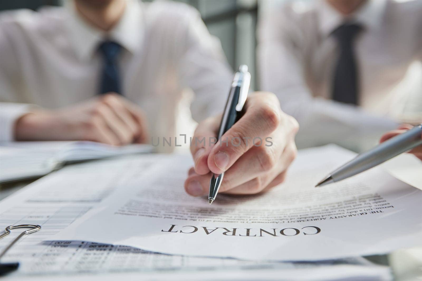 Close-up of businessmen reviewing a close-up contract while sitting at a table