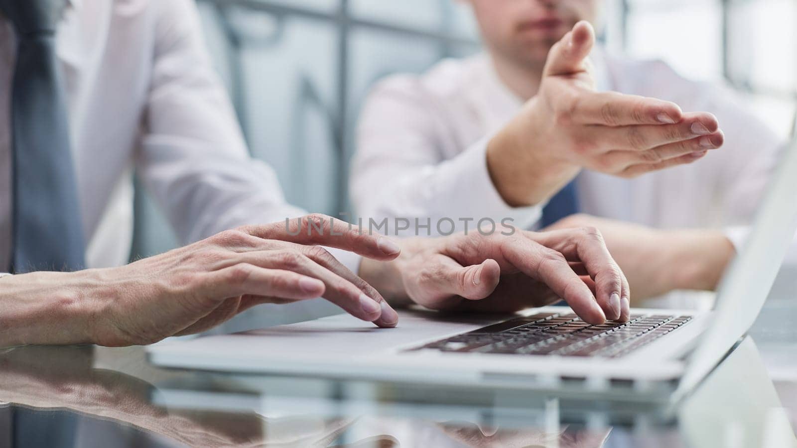 Closeup view of two young coworkers working on mobile laptop computer at office