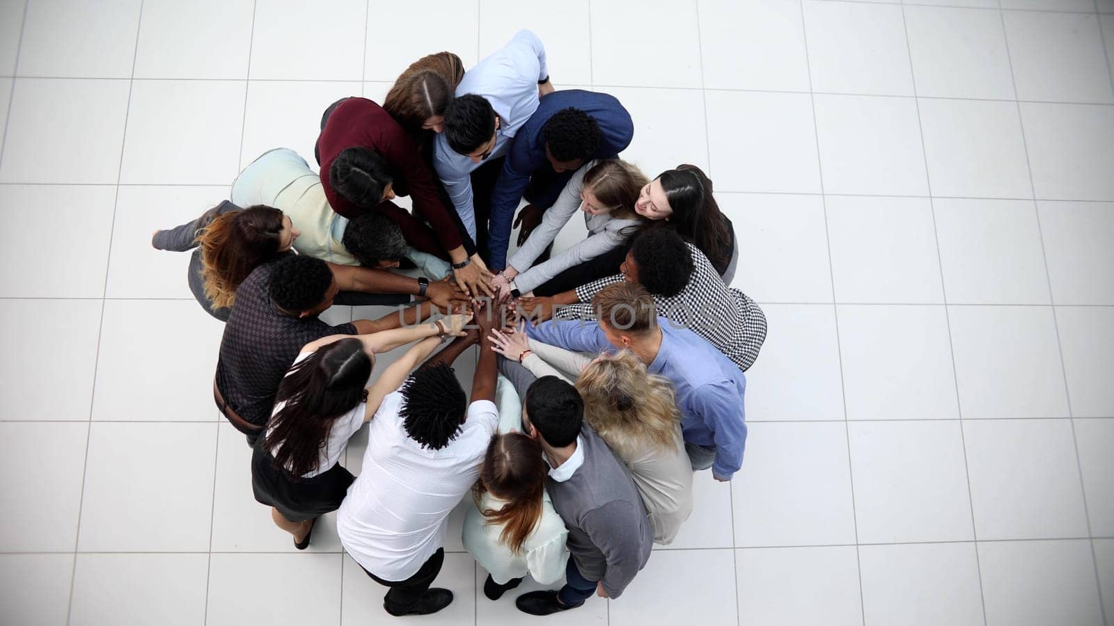 Friends with stack of hands showing unity and teamwork.