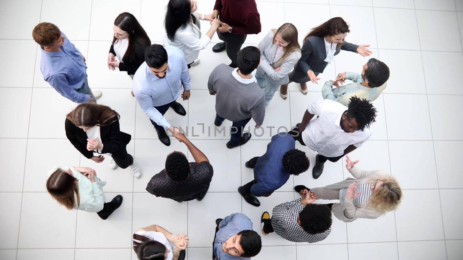 multinational office workers and foreign employees stand and talk in the office lobby.Top view. by Prosto
