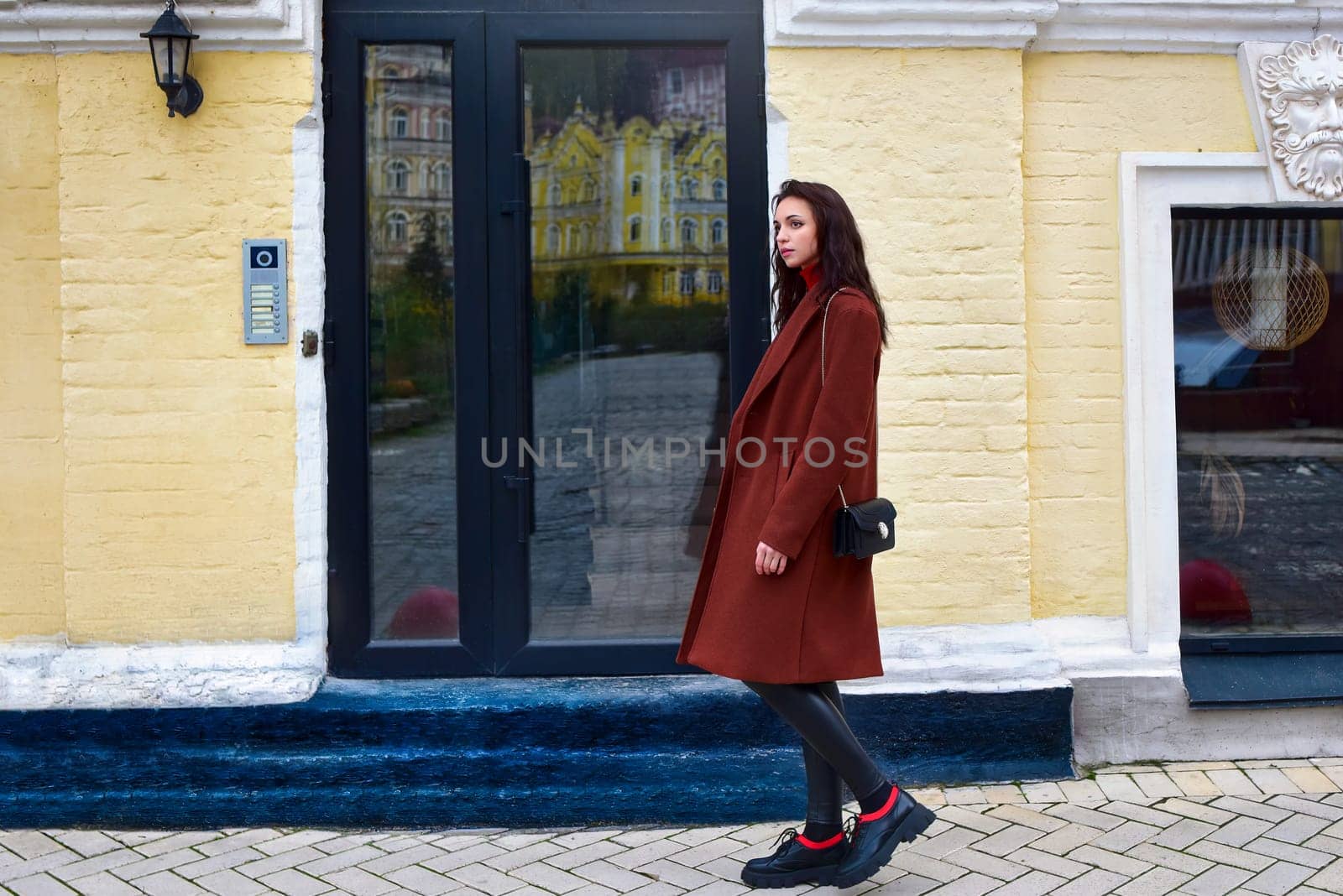 Young woman walks down the street in a brown coat