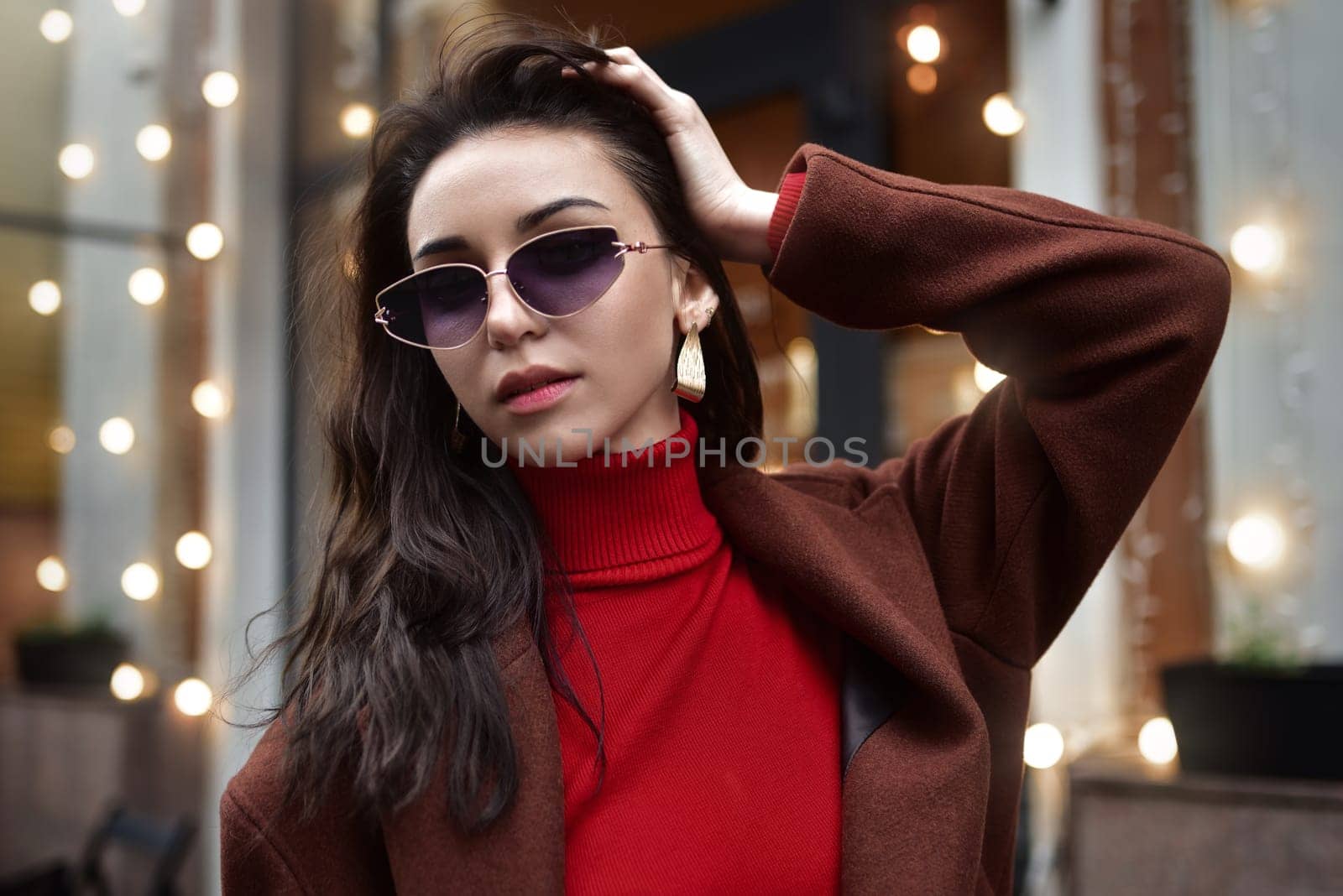 Portrait of a Woman in sunglasses fixing her hair on the street.