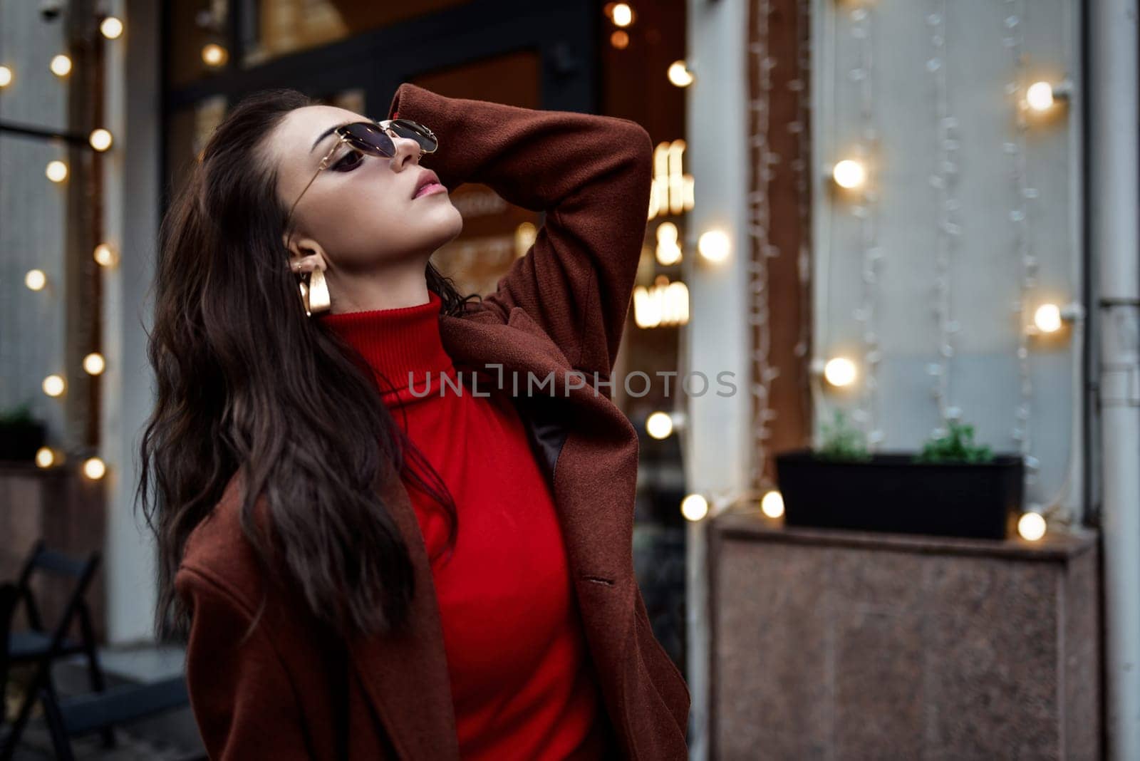 Beautiful fashionable woman in sunglasses fixing hair on the street.