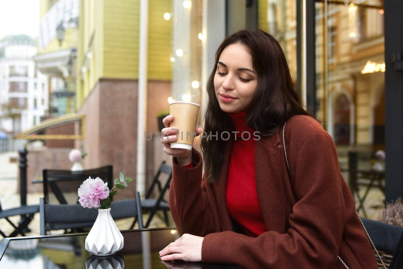 attractive Woman smiling with a cup of coffee outside, drinking coffee on the terrace in a cafe.