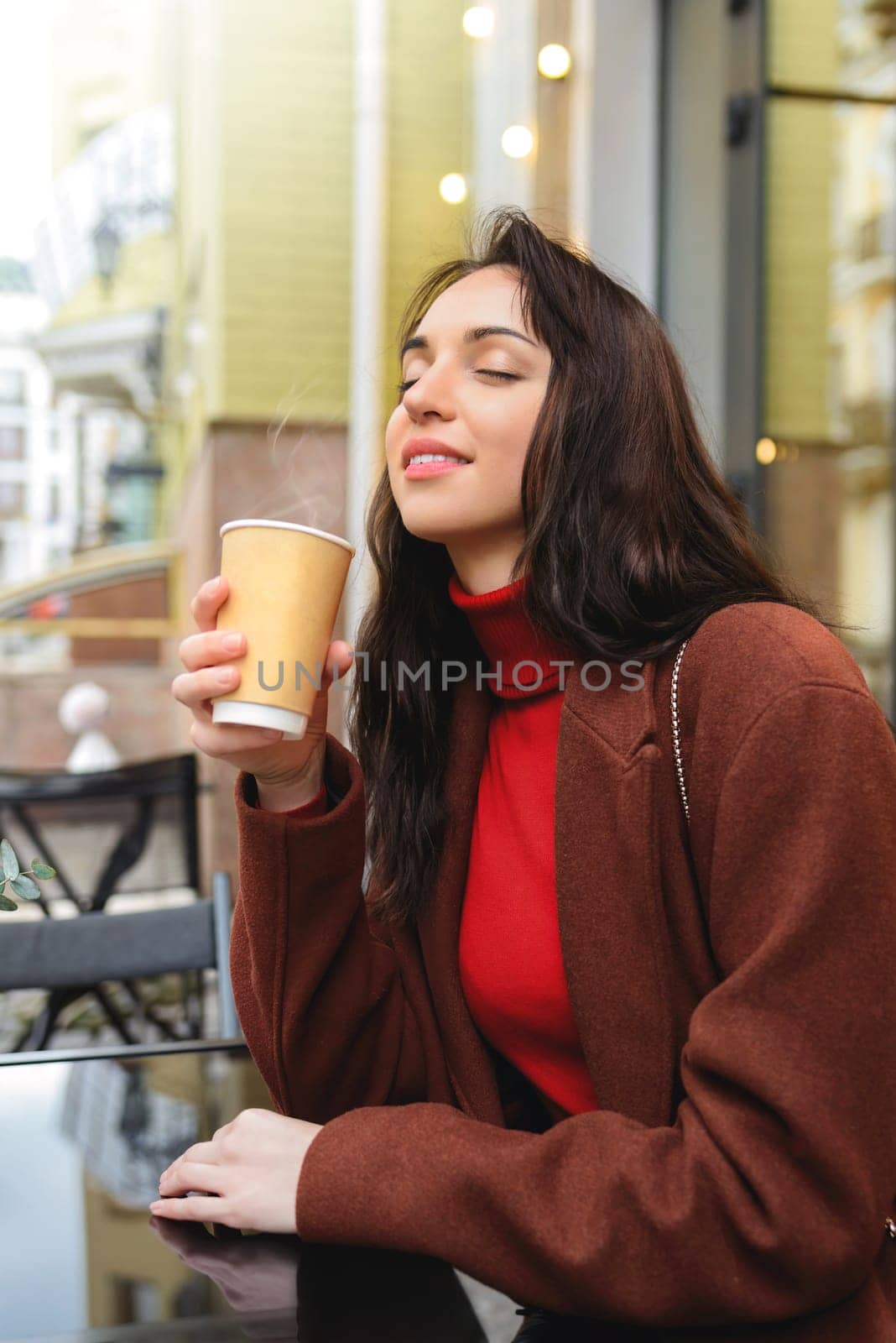 Young pretty Woman enjoying the aroma of coffee on the street.