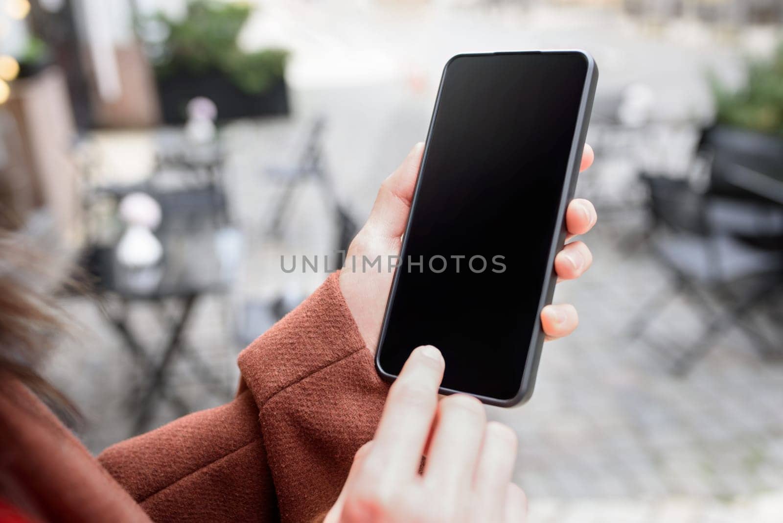 Cropped image of woman's hands holding smart phone with blank copy space screen for your text message or promotional content by Nickstock