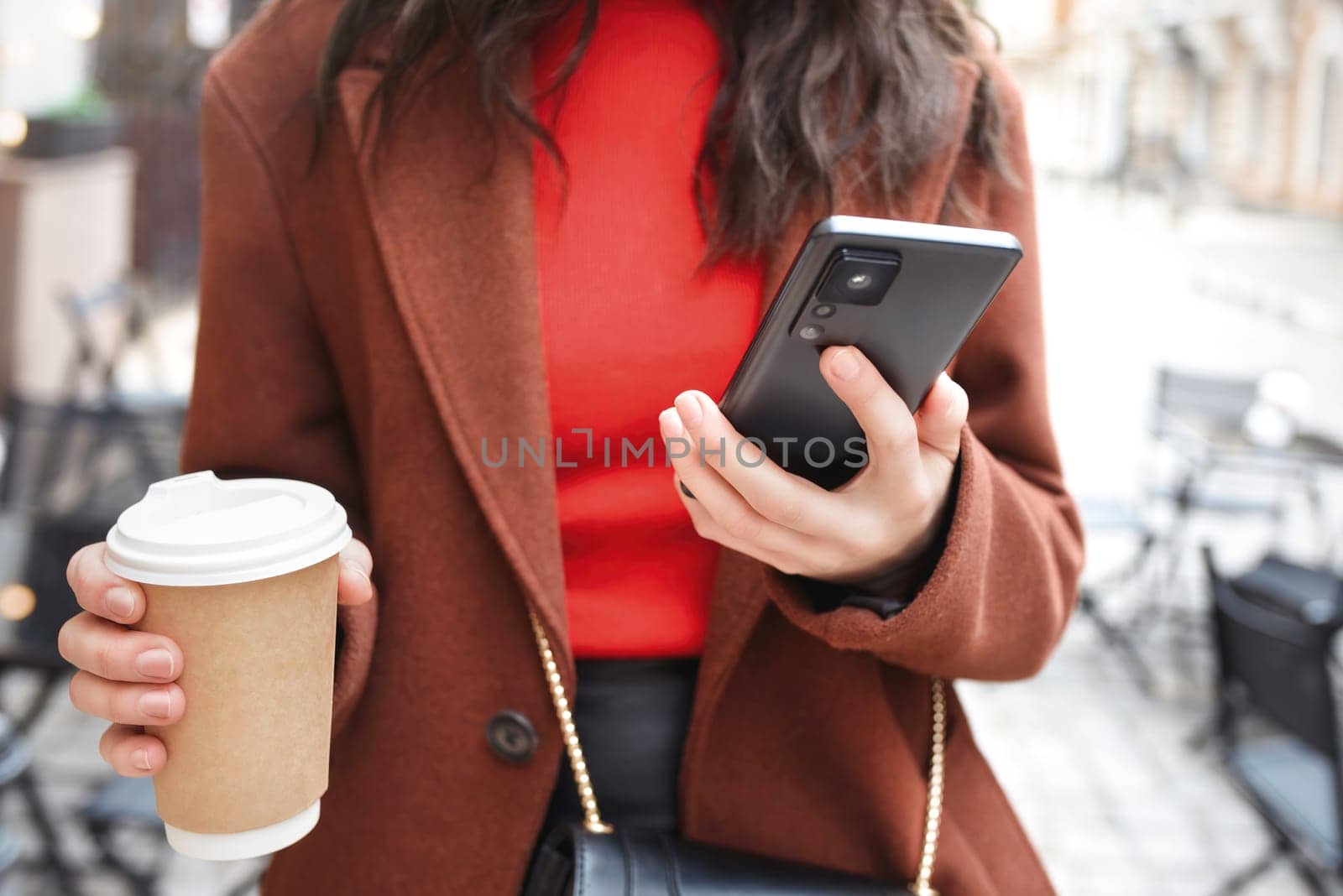 woman uses a smartphone, chats with someone on the street and drinks coffee