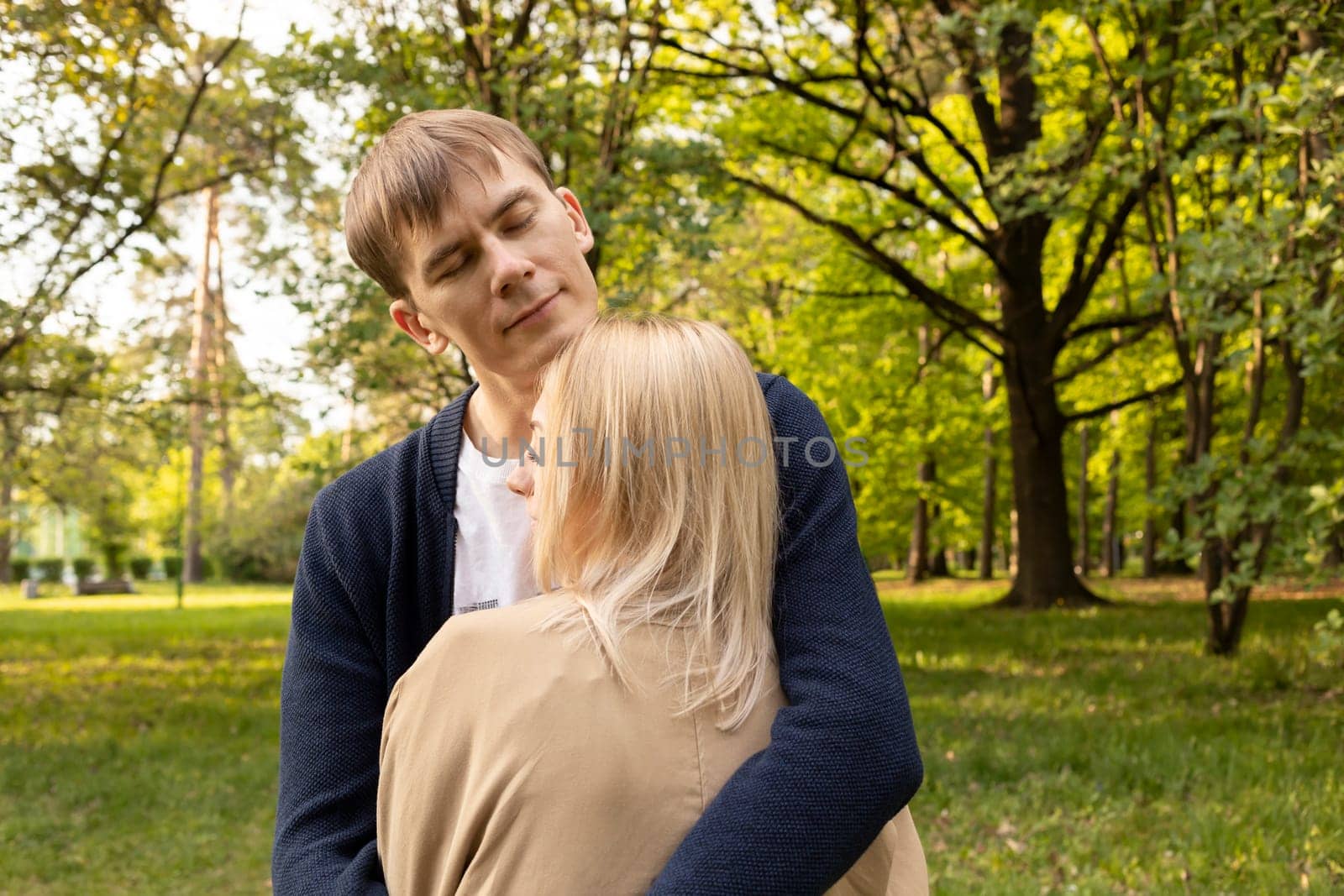 Beautiful Couple Stands Hugging With Closed Eyes In Green Park. Relationship, Togetherness. Enjoying Time Together, Harmony. Pure Feelings. Horizontal Plane Summer Time. High quality photo