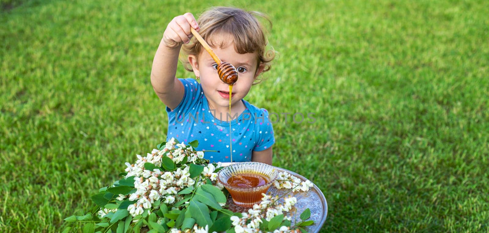 The child eats honey in the garden. Selective focus. by yanadjana