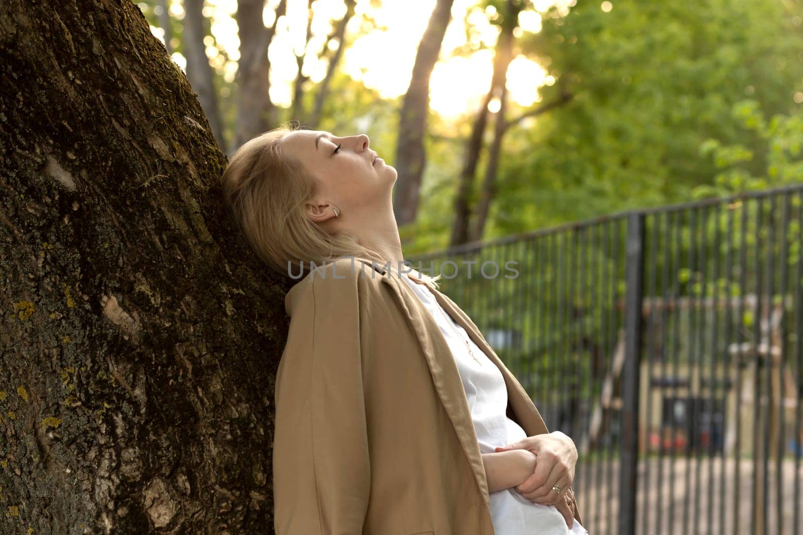Tired White Woman Leans To Tree, Closed Her Eyes In Summer Time on Sunset. Rest And Recharge in Nature, Self Awareness, Leisure Time, Mental Health. Copy Space For Text Horizontal Plane.