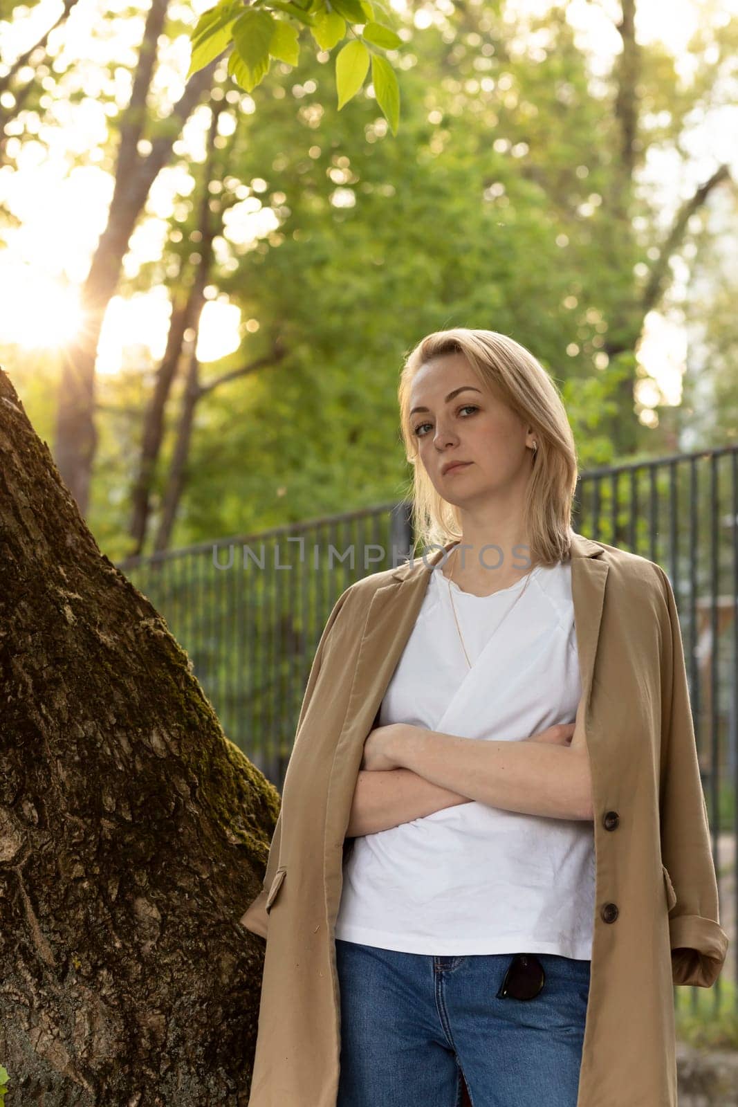 Tired White Woman Stand Near Tree With Crossed Hands, Looking At Camera on Sunset. Rest And Recharge in Nature, Self Awareness, Leisure Time, Mental Health. Copy Space For Text Vertical Plane.