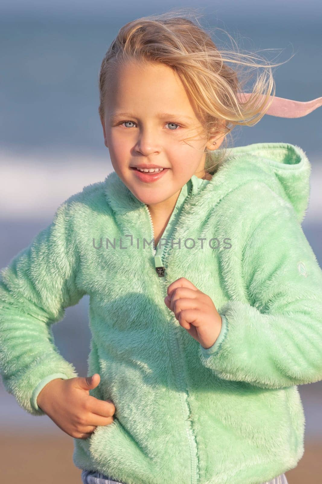 A 5-year-old girl in a green jacket is running by gcm