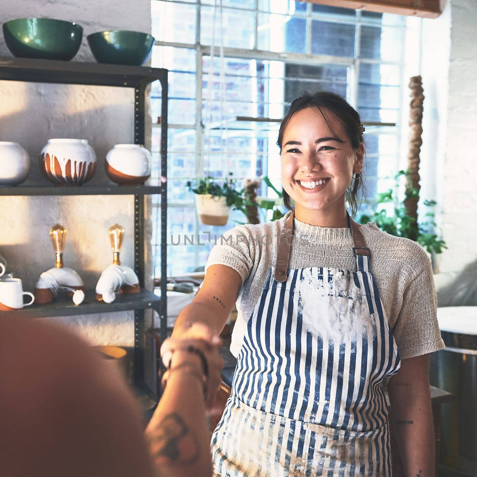 Time to make ceramic magic. two young women shaking hands in a pottery studio