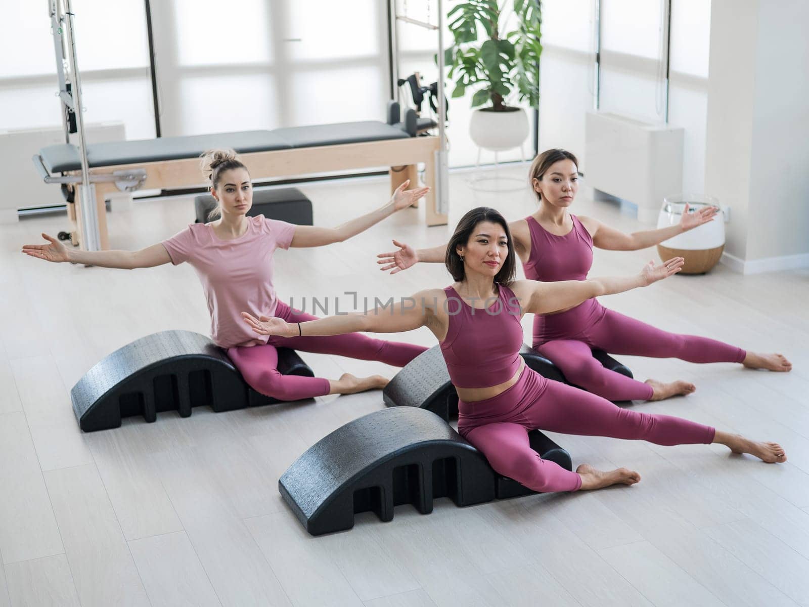 Balanced Body Pilates Arc. Three asian women exercising on pilates arc. by mrwed54