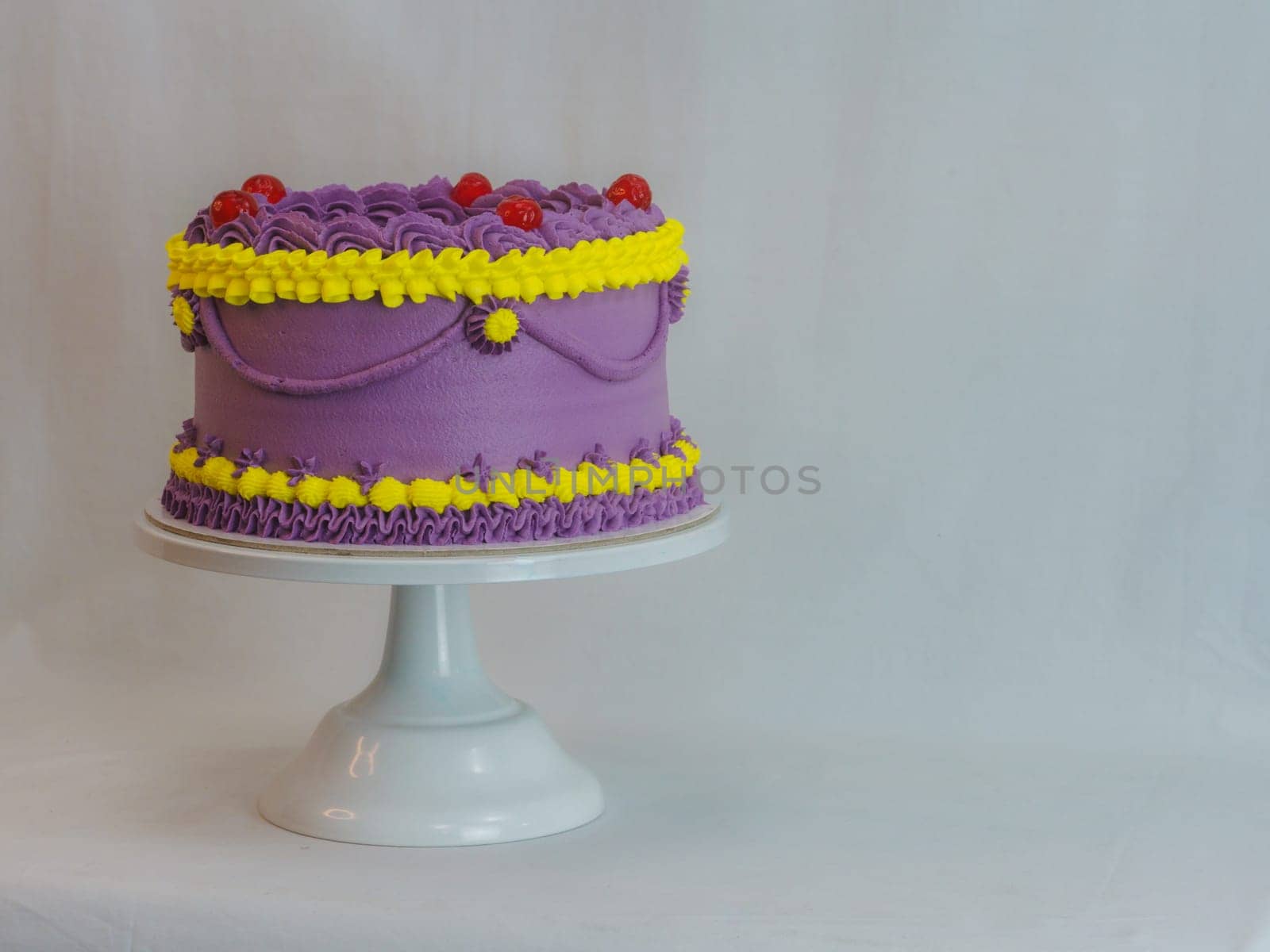 frosted icing violet yellow classic cilindrical cake on studio by verbano