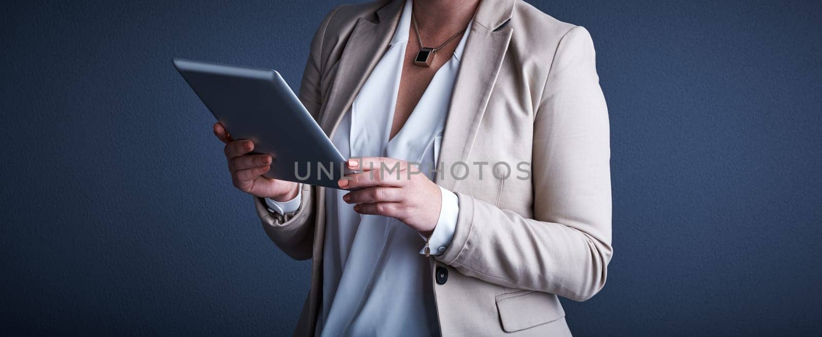 Taking advantage of technology. Studio shot of an unrecognizable corporate businesswoman using a tablet against a dark background