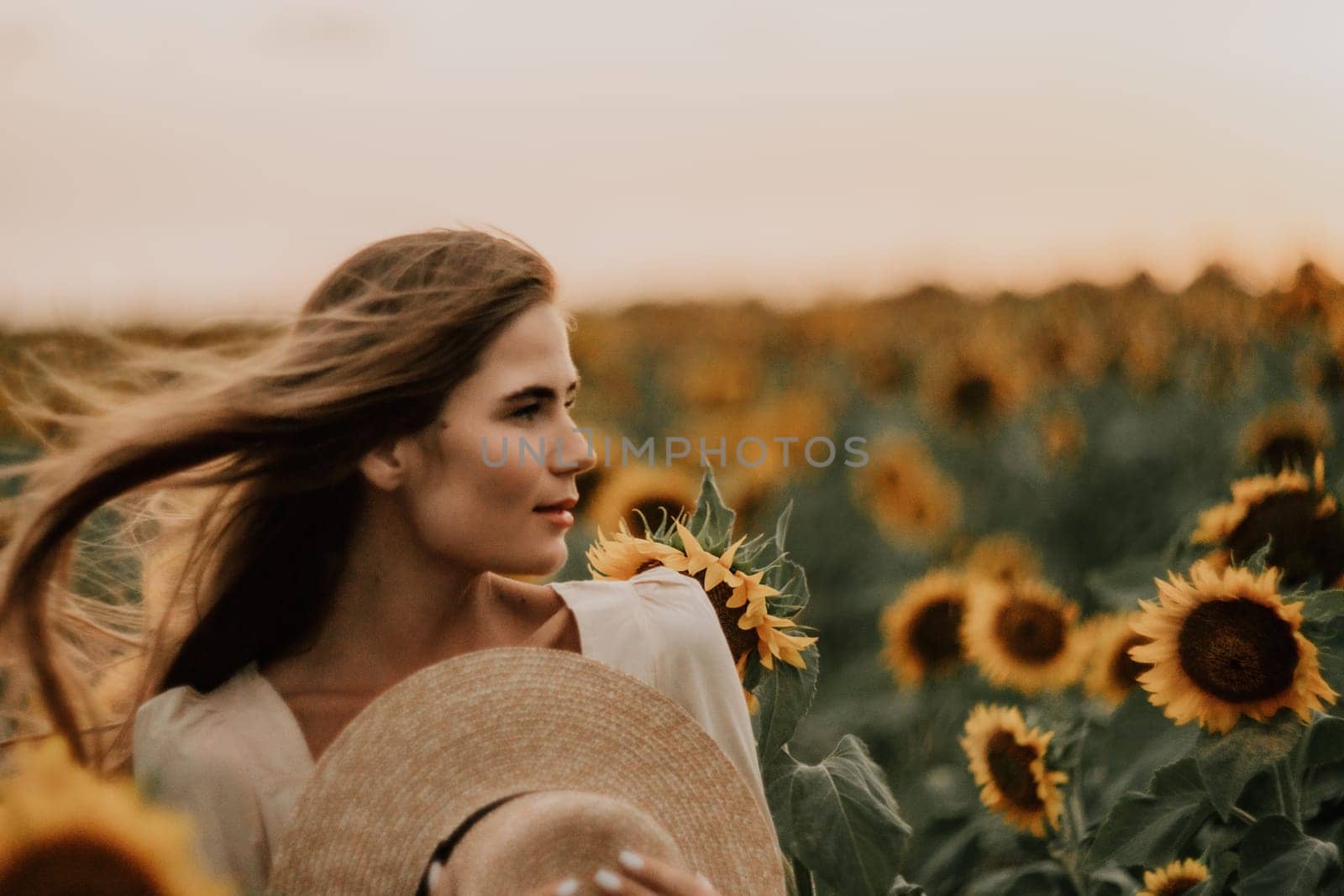 Woman in Sunflower Field: Happy girl in a straw hat posing in a vast field of sunflowers at sunset, enjoy taking picture outdoors for memories. Summer time. by panophotograph