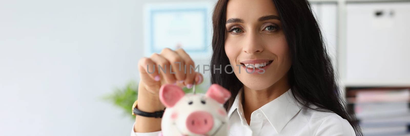 Portrait of smiling woman throwing coin into piggy bank. Favorable bank deposits and financial savings