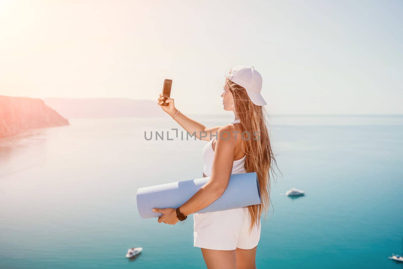 Young woman with black hair, fitness instructor in pink sports leggings and tops, doing pilates on yoga mat with magic pilates ring by the sea on the beach. Female fitness daily yoga concept