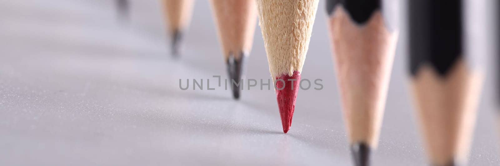 Red pencil stands out from crowd of many identical black pencils. Unique creative ideas for project