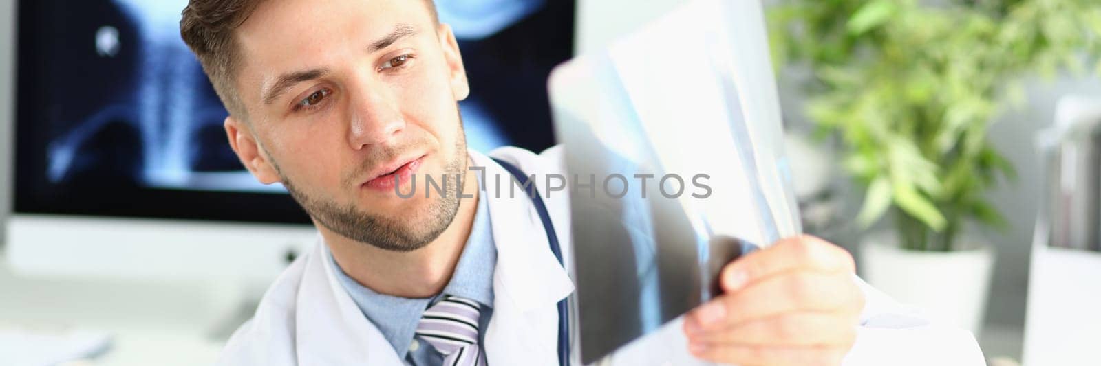 Male doctor examines x-ray of leg and arm in clinic. Medical diagnosis of fractures concept